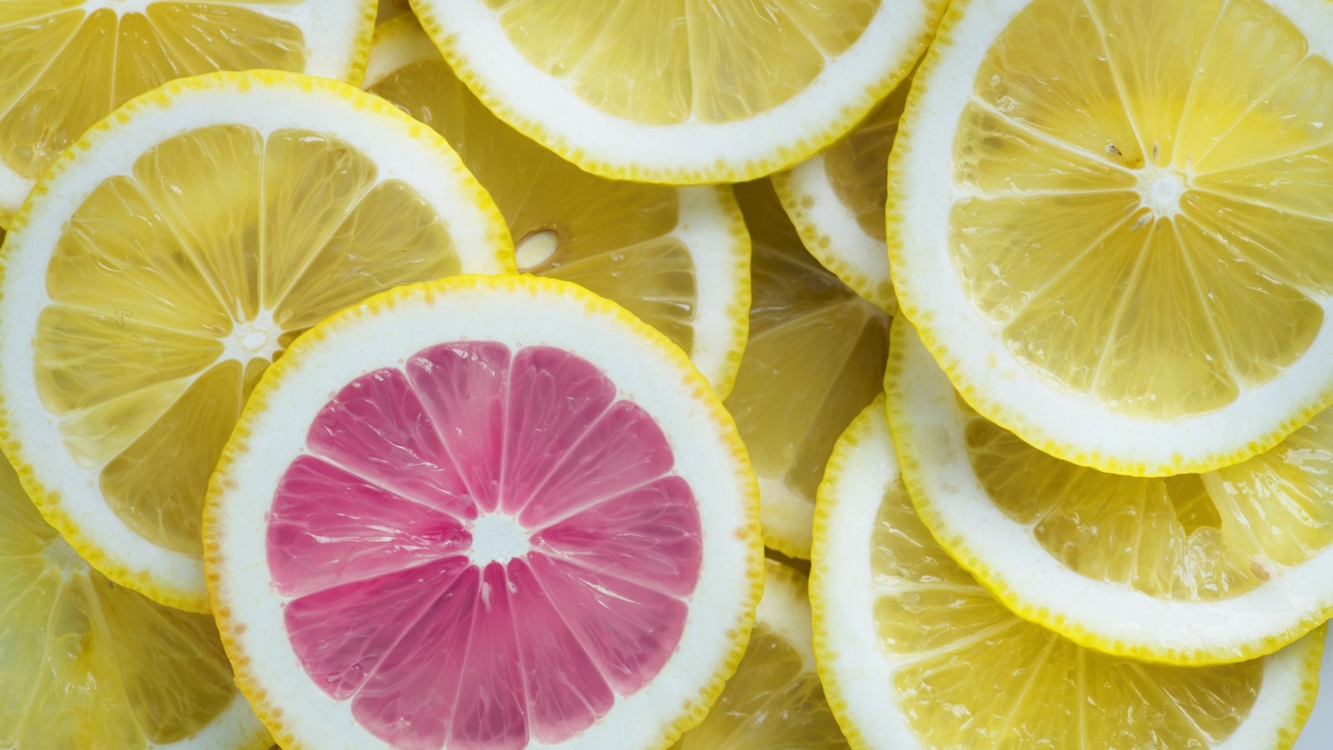 Close-up of sliced lemons and one pink lemon HD Wallpaper