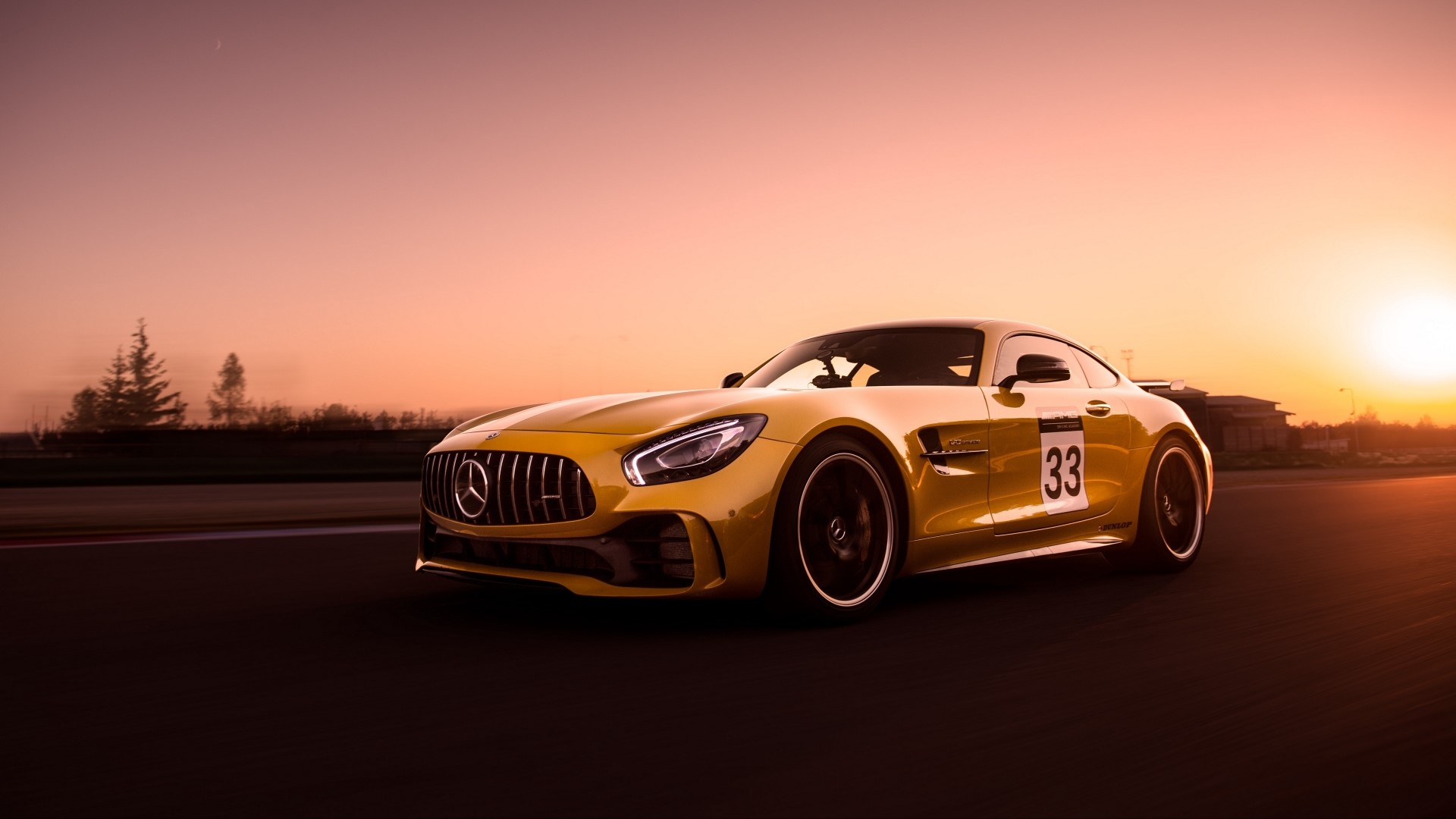 Yellow Mercedes-Benz GT R on a race track at sunset HD Wallpaper