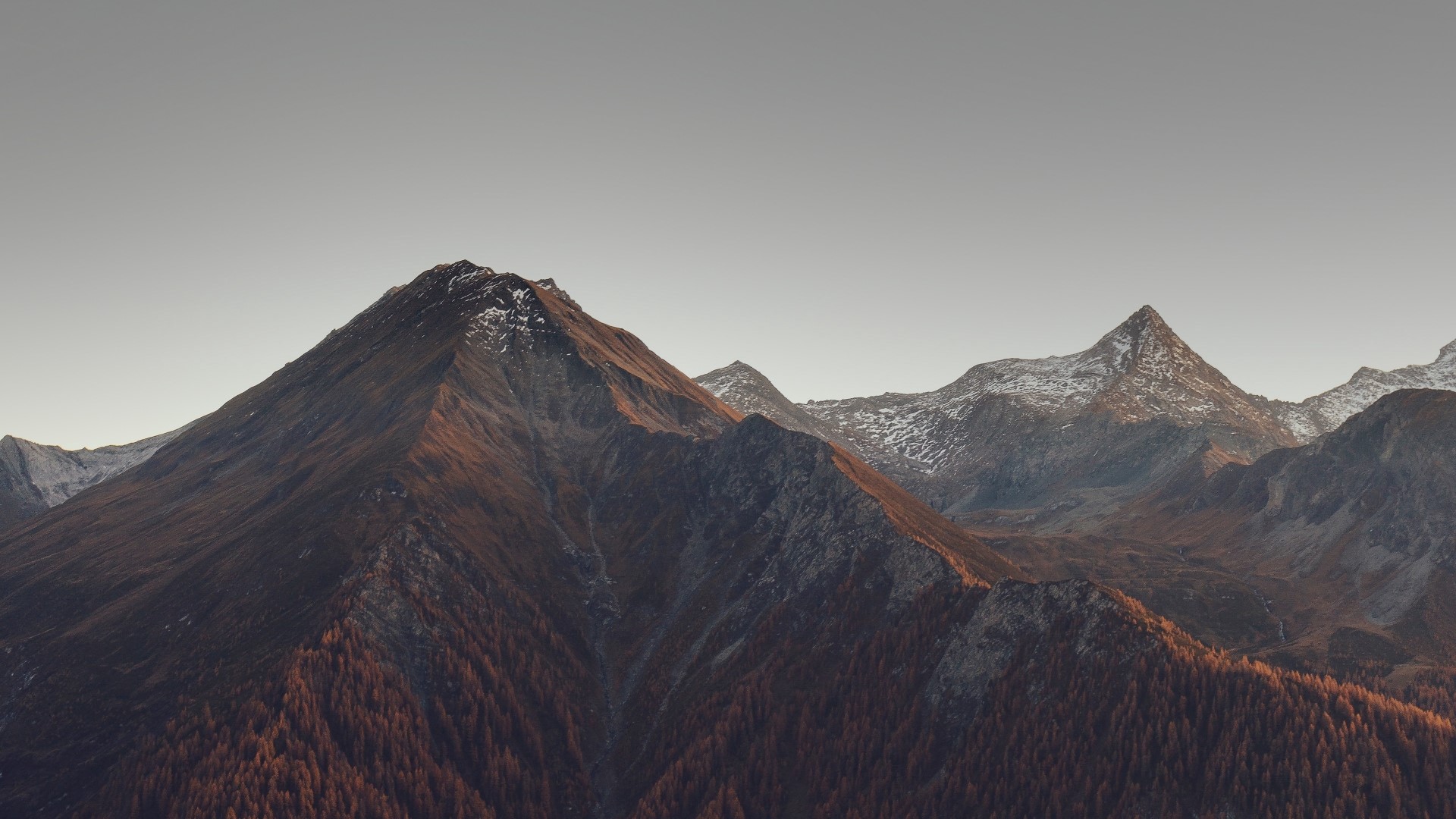 Mountain range with snow-capped peaks and autumn trees HD Wallpaper
