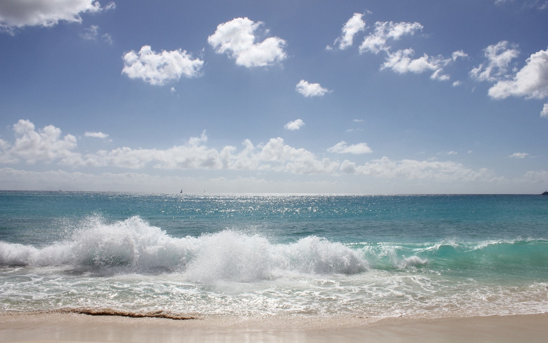 Ocean waves crashing on a sandy beach under a cloudy sky HD Wallpaper