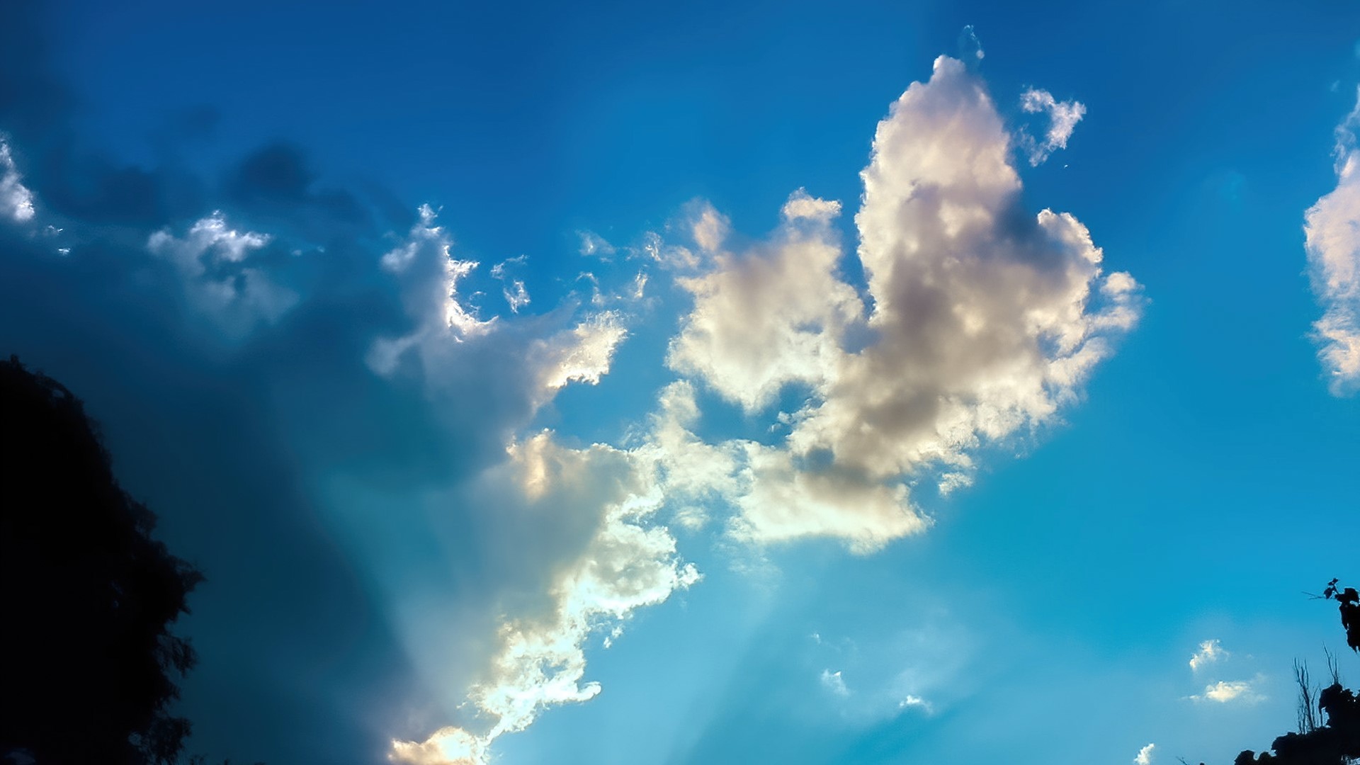 Sunlight beams through dramatic clouds in a blue sky HD Wallpaper