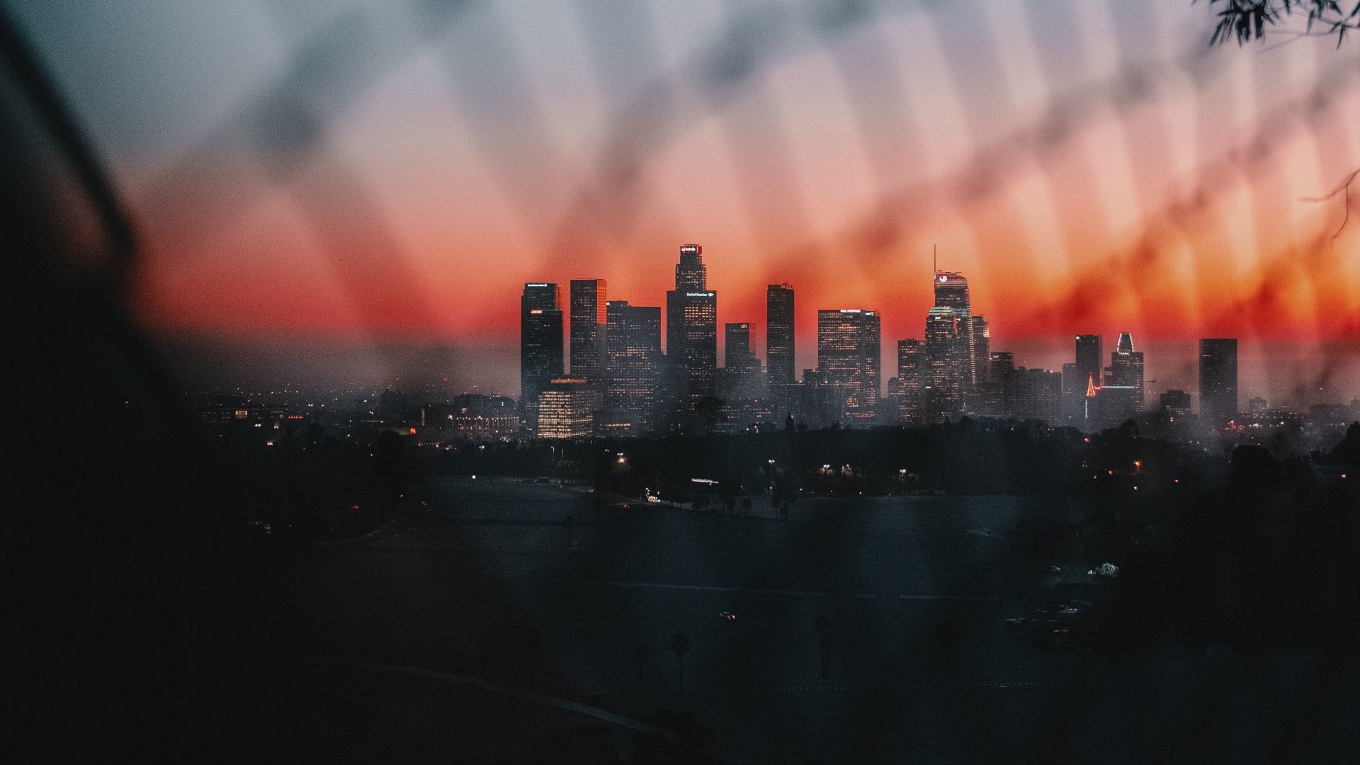 Cityscape at sunset with light beams HD Wallpaper