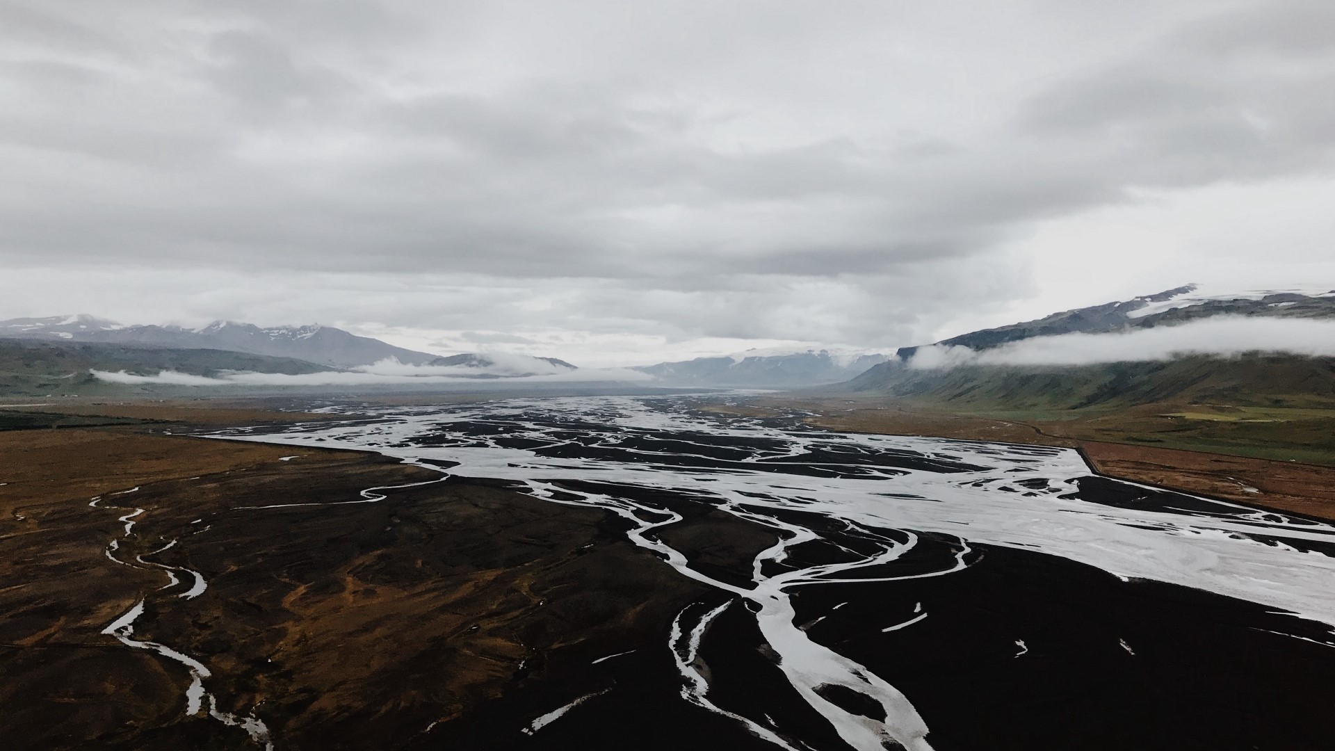 Aerial view of a braided river in a valley with mountains HD Wallpaper