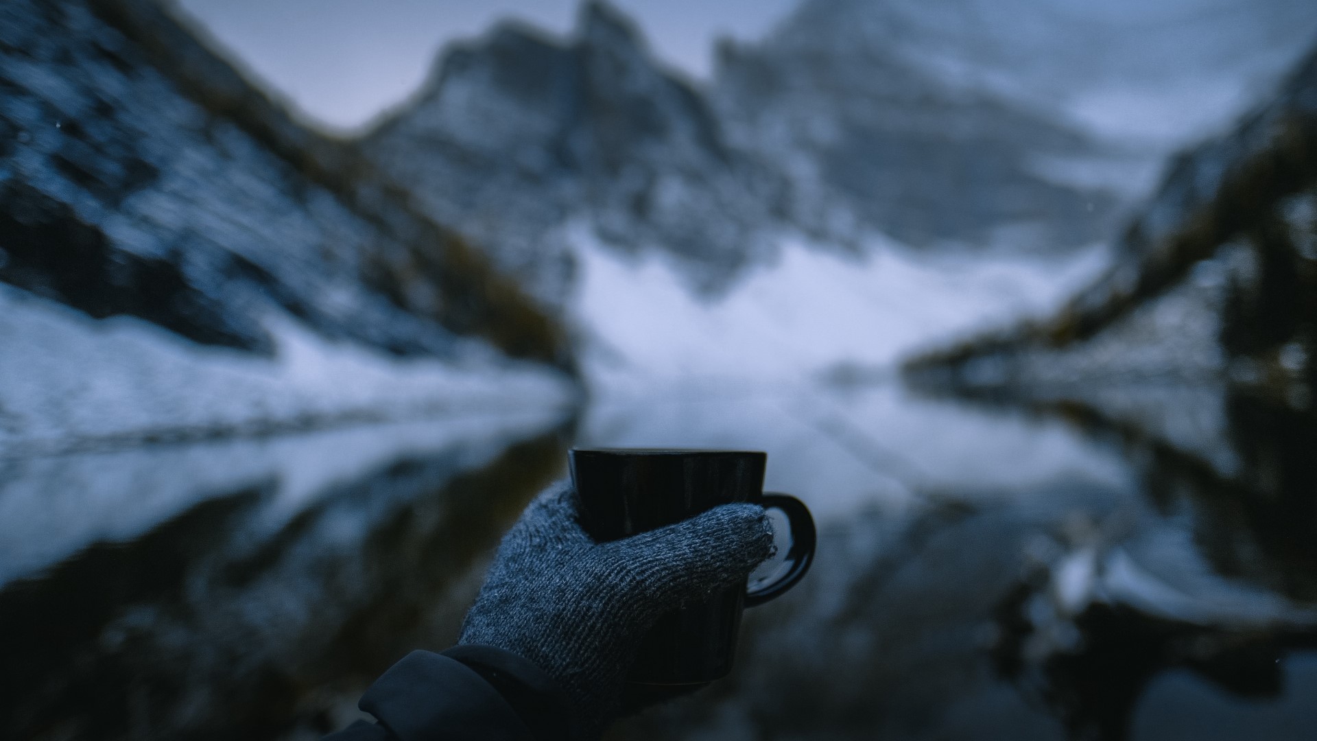 Person holding a cup by a lake with mountains HD Wallpaper