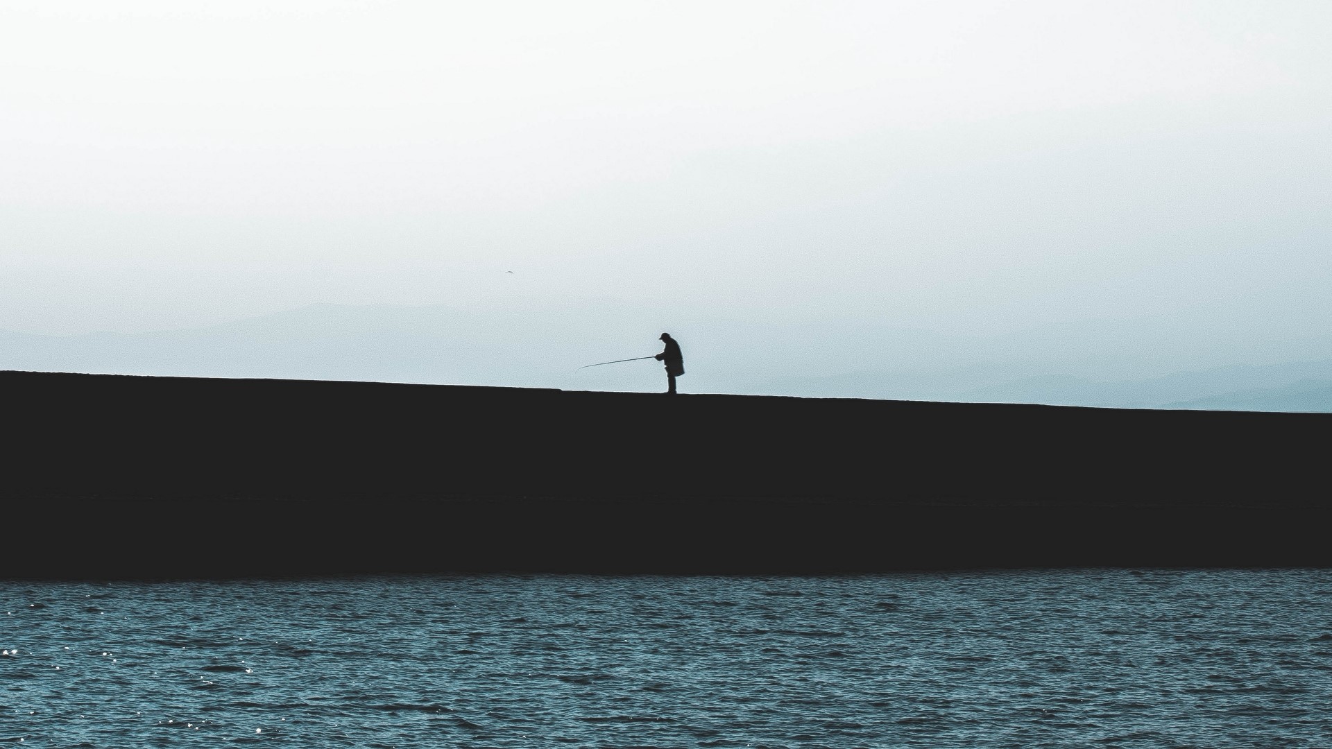 Fisherman on a wall by the sea HD Wallpaper