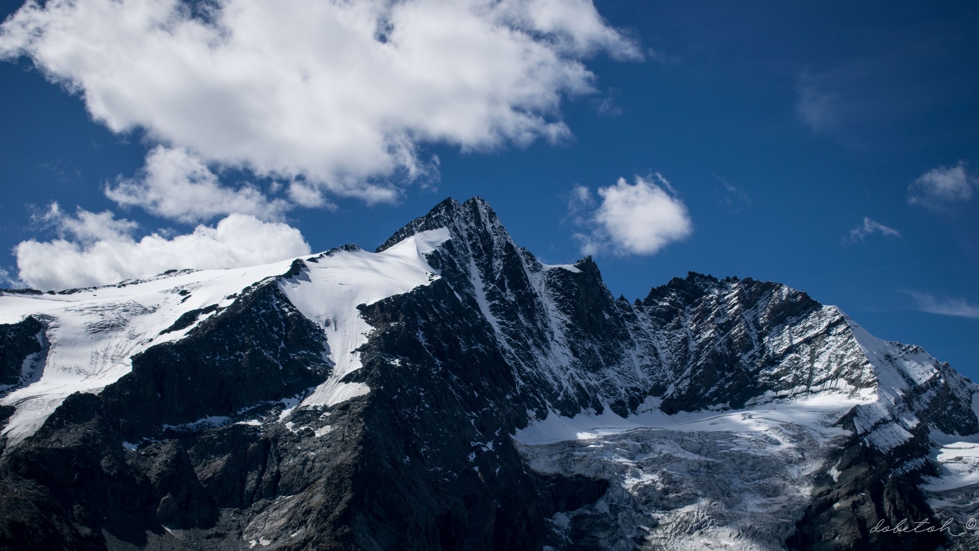 Snow-capped mountain range under a blue sky with clouds HD Wallpaper