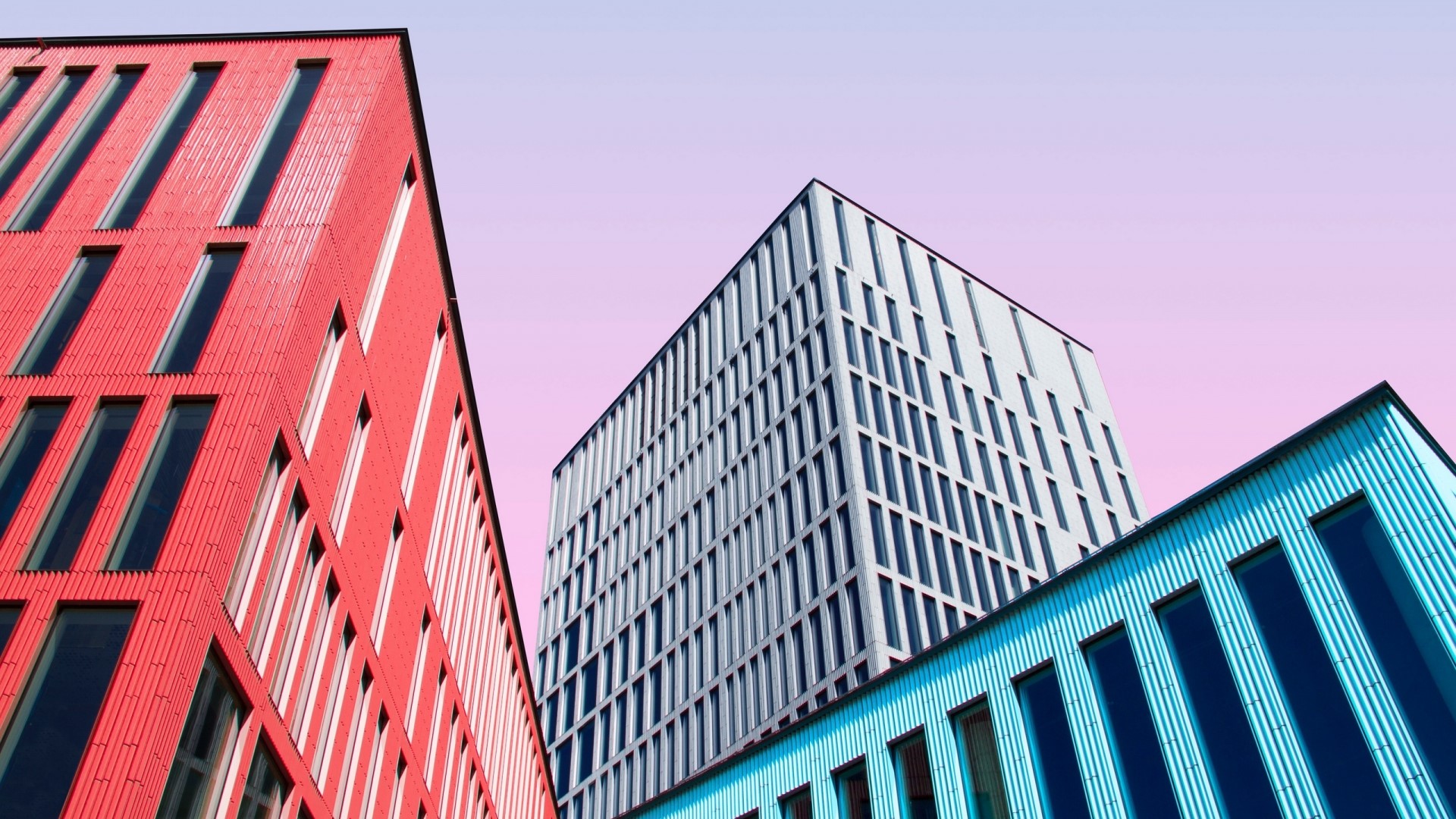 Modern buildings with colorful facades against a pink sky HD Wallpaper