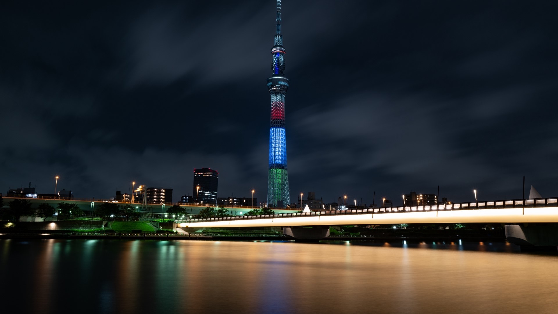 Tokyo Skytree illuminated at night over river and bridge HD Wallpaper