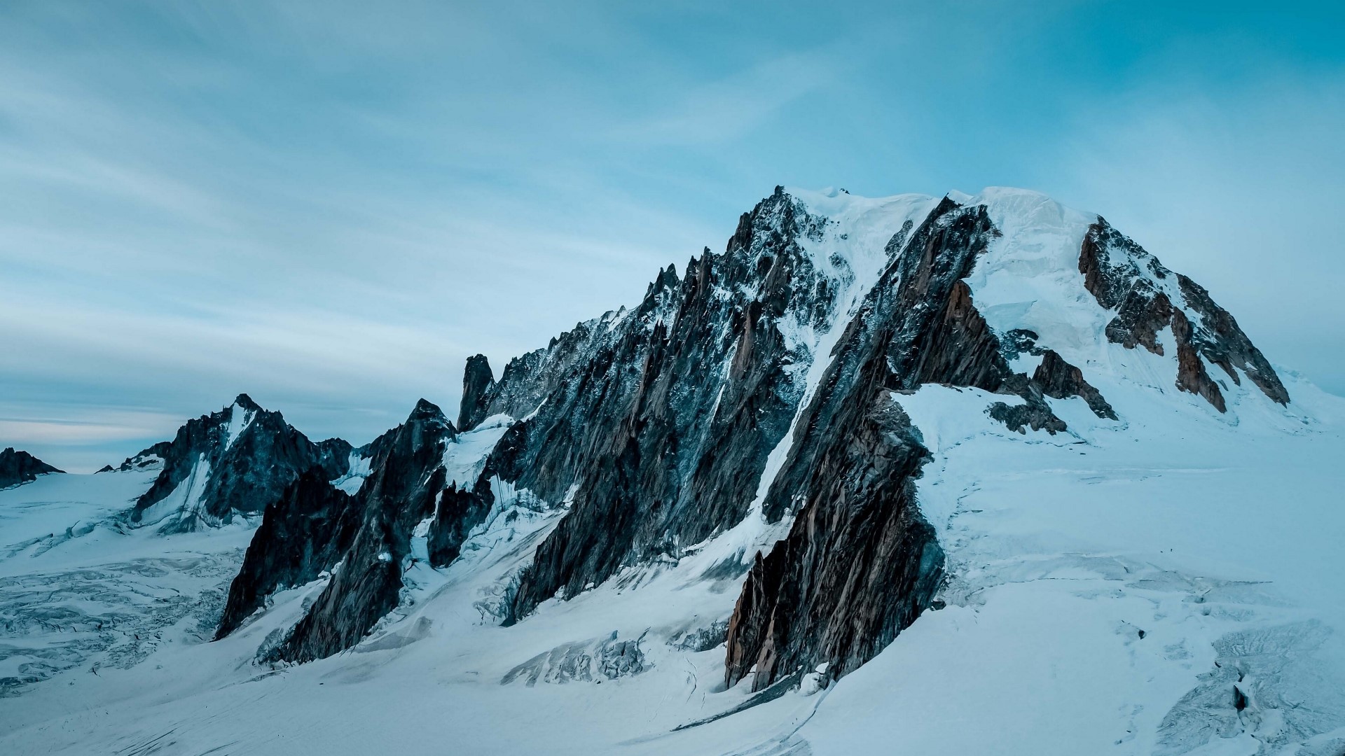 Snowy Mountain Peaks Under a Cloudy Sky HD Wallpaper