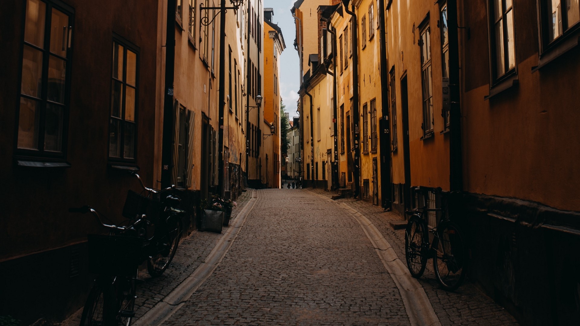Narrow cobblestone street between old buildings HD Wallpaper