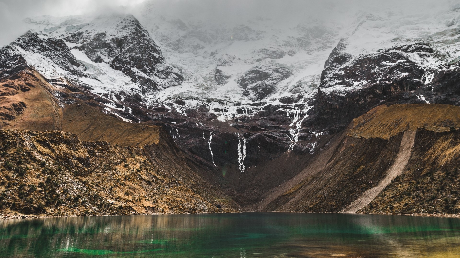 Snow-capped mountains above a clear lake HD Wallpaper