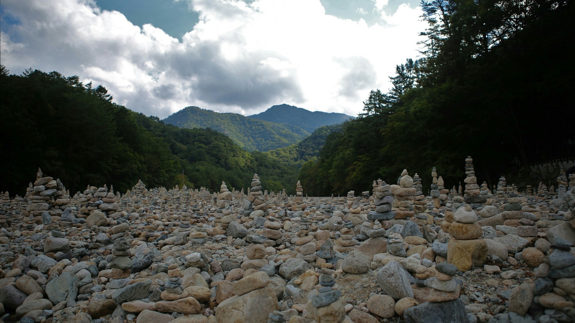 Stone cairns in a mountain valley HD Wallpaper