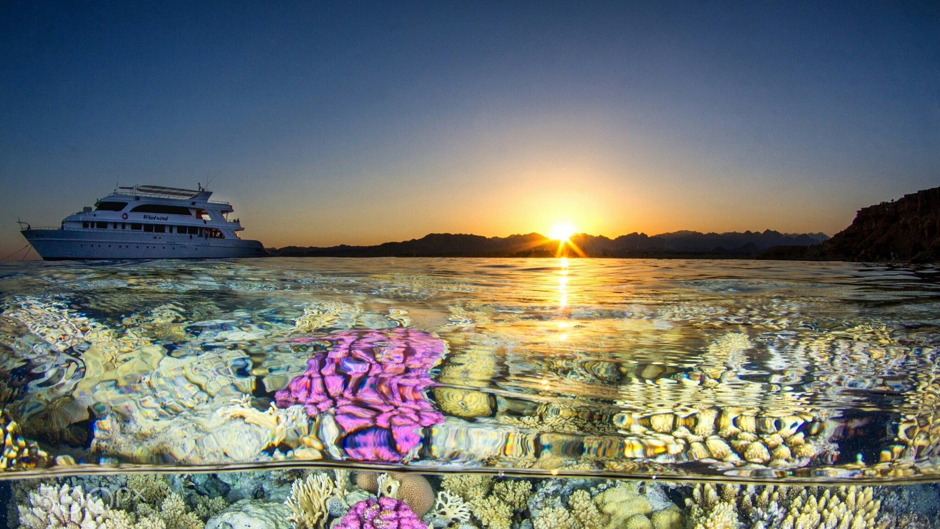 Split view of a yacht and coral reef at sunset HD Wallpaper
