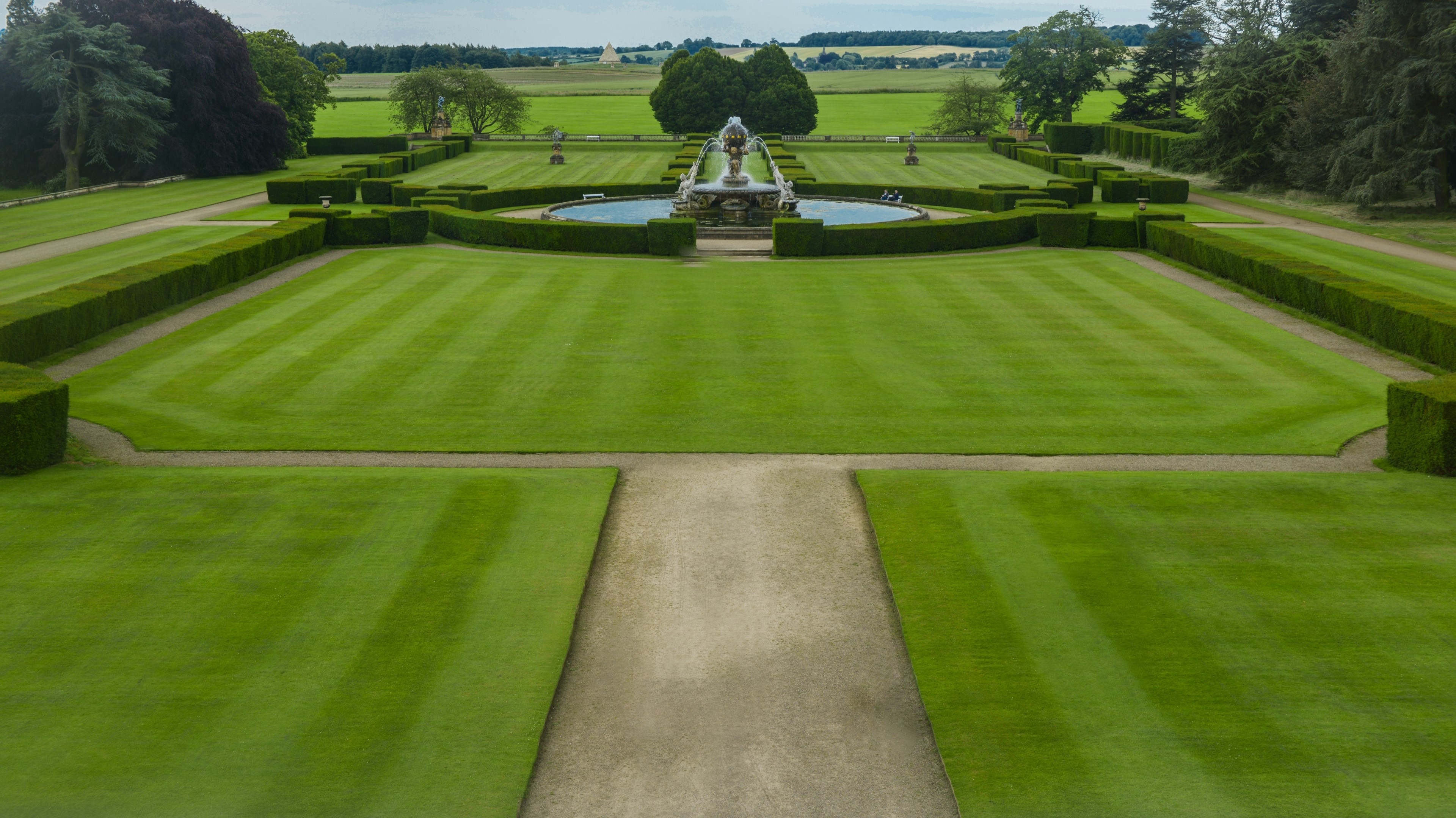 Formal garden with fountain and manicured lawns HD Wallpaper