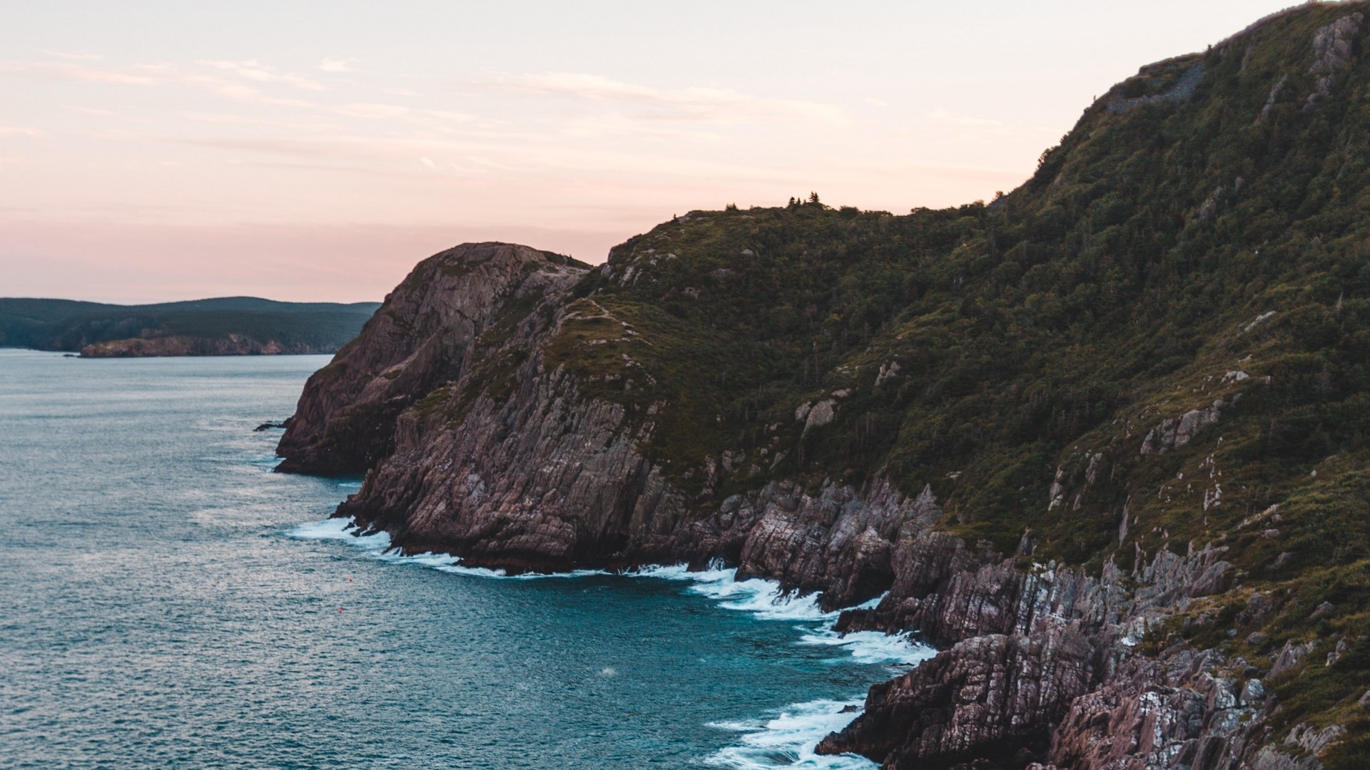 Rocky coastline with ocean waves and hills HD Wallpaper