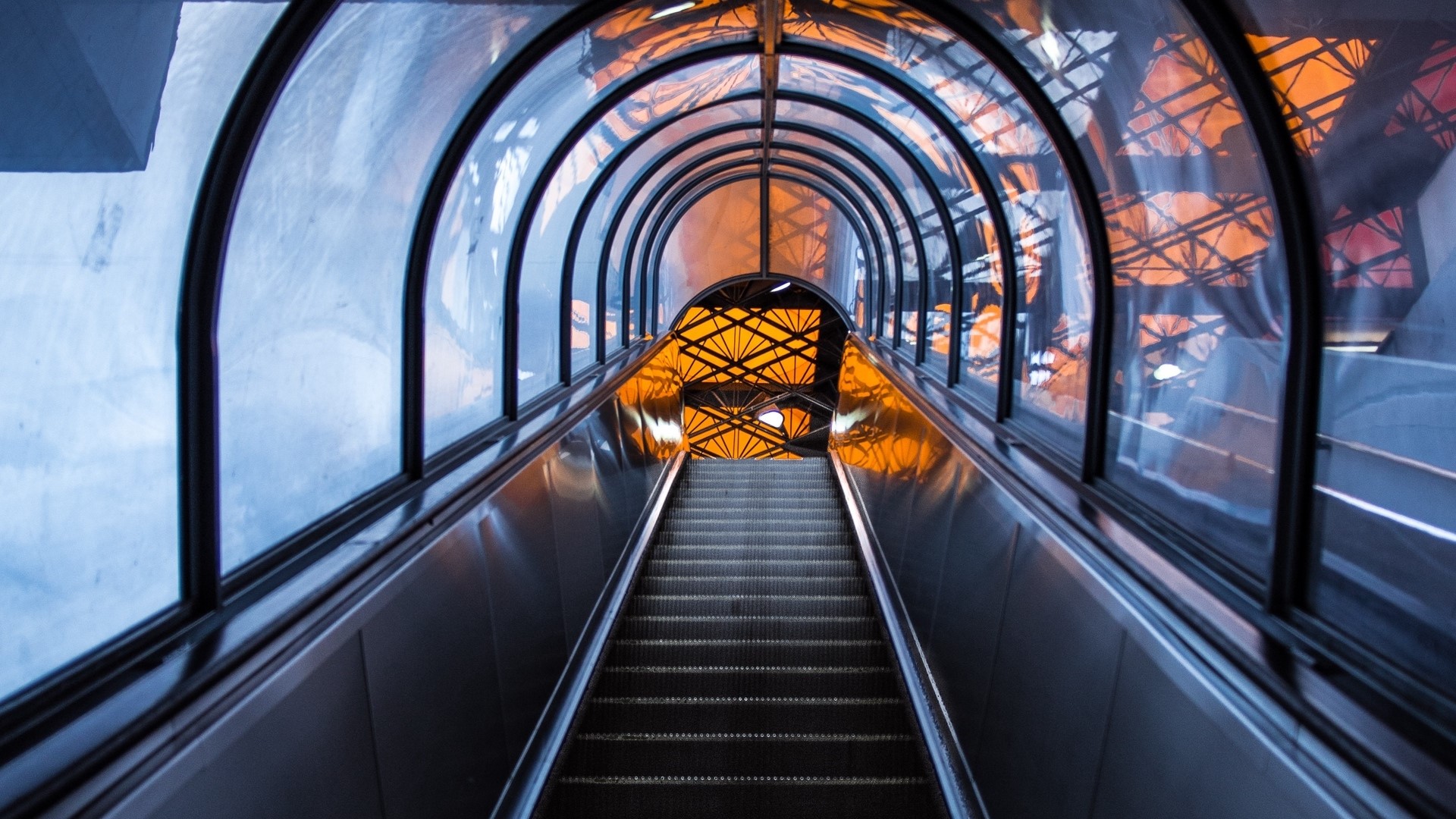 Escalator tunnel with glass roof and orange structure HD Wallpaper