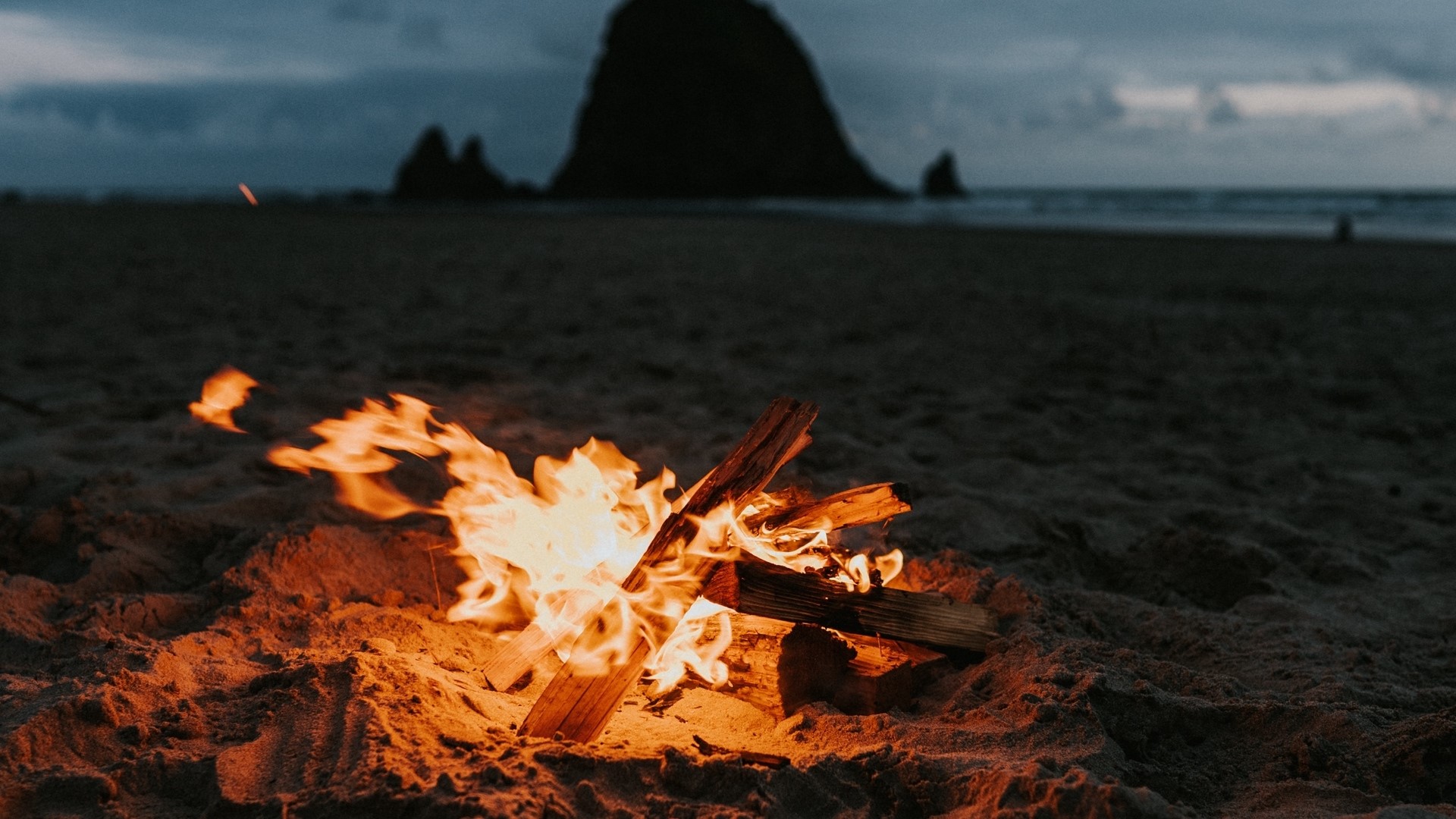 Bonfire on a beach at dusk HD Wallpaper