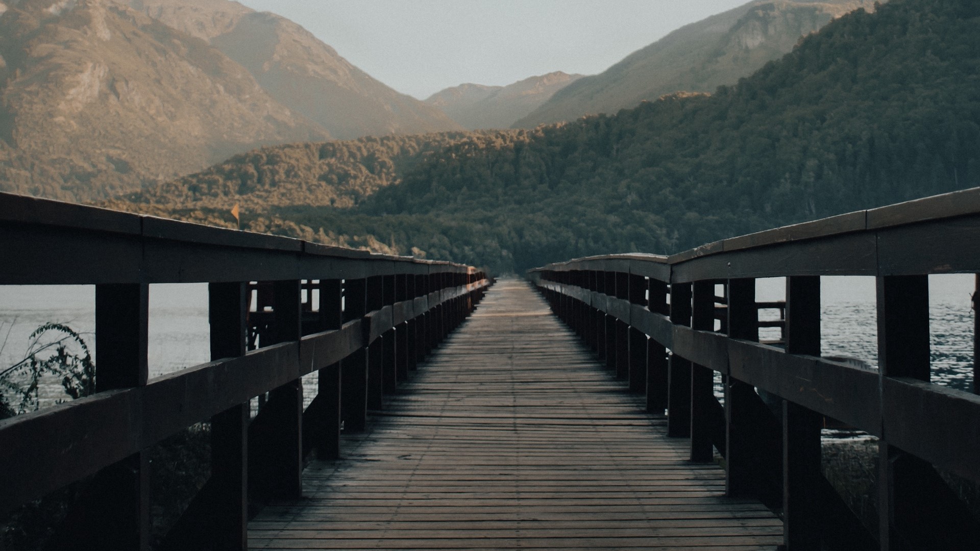 Wooden bridge over water with mountains in background HD Wallpaper