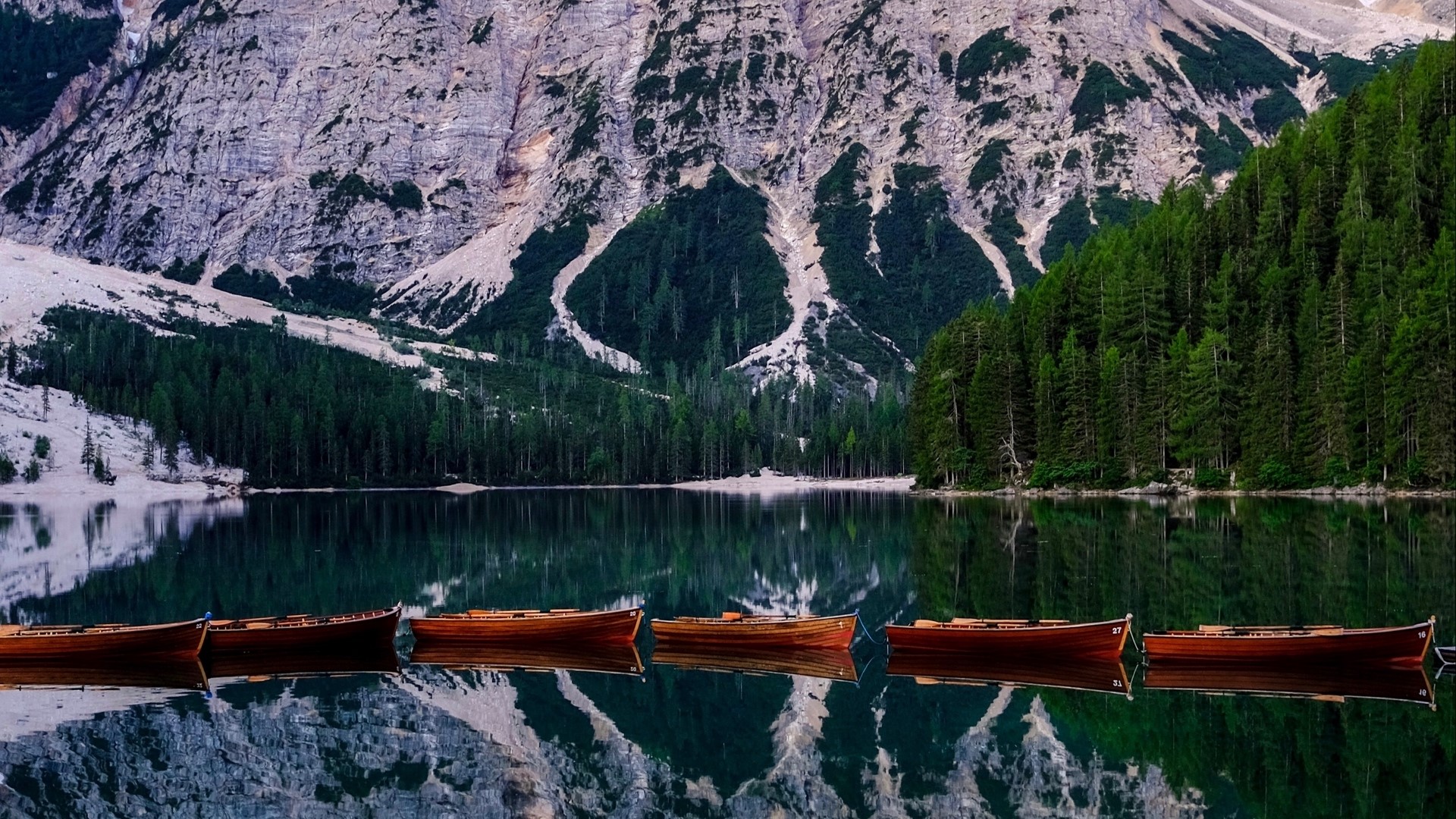 Wooden boats on a calm lake with mountains and forest HD Wallpaper