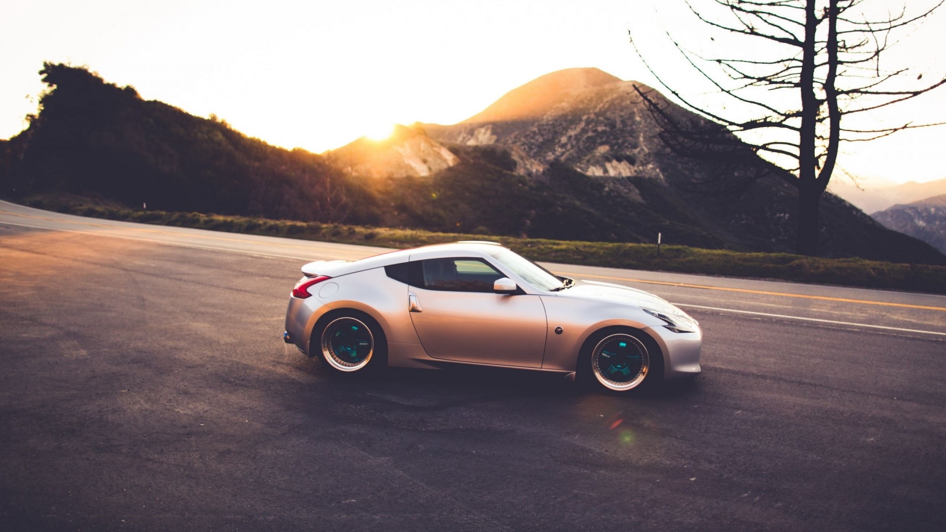 Silver Nissan 370Z on a mountain road at sunset HD Wallpaper