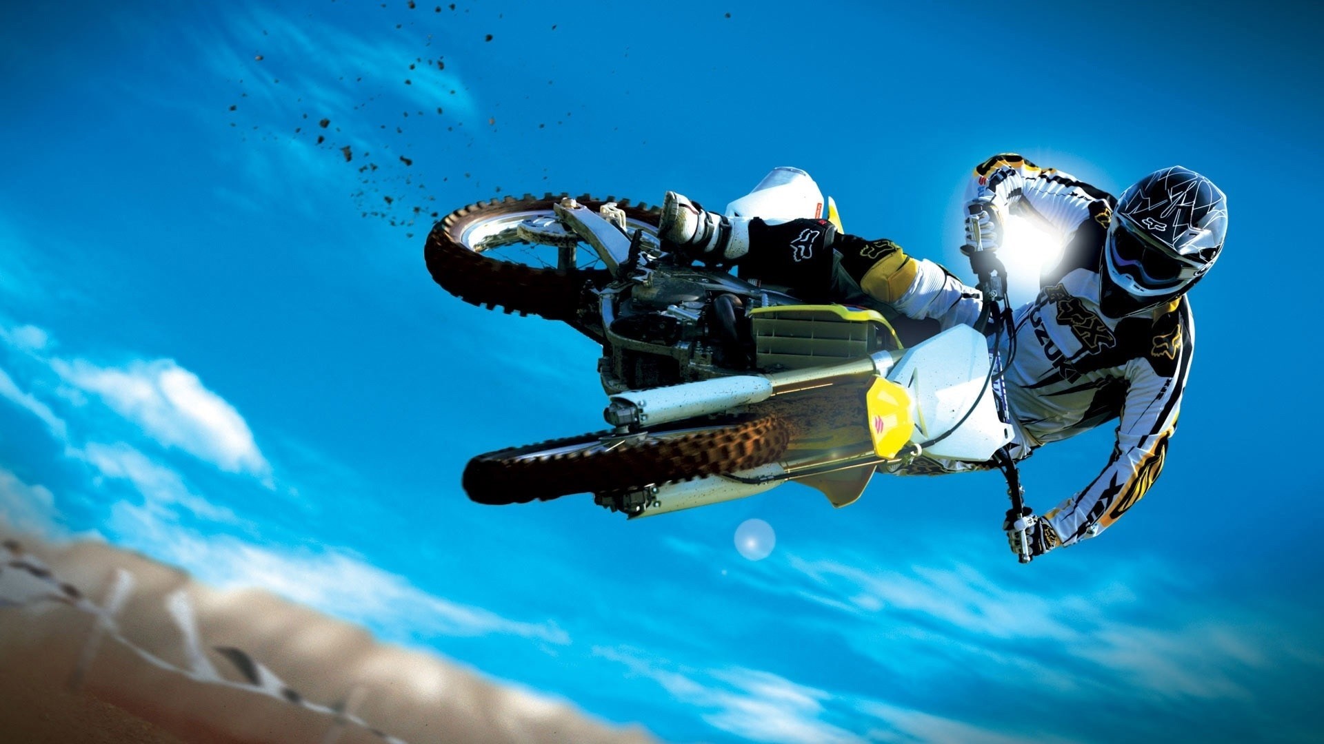 Motocross rider performing a jump against a blue sky HD Wallpaper
