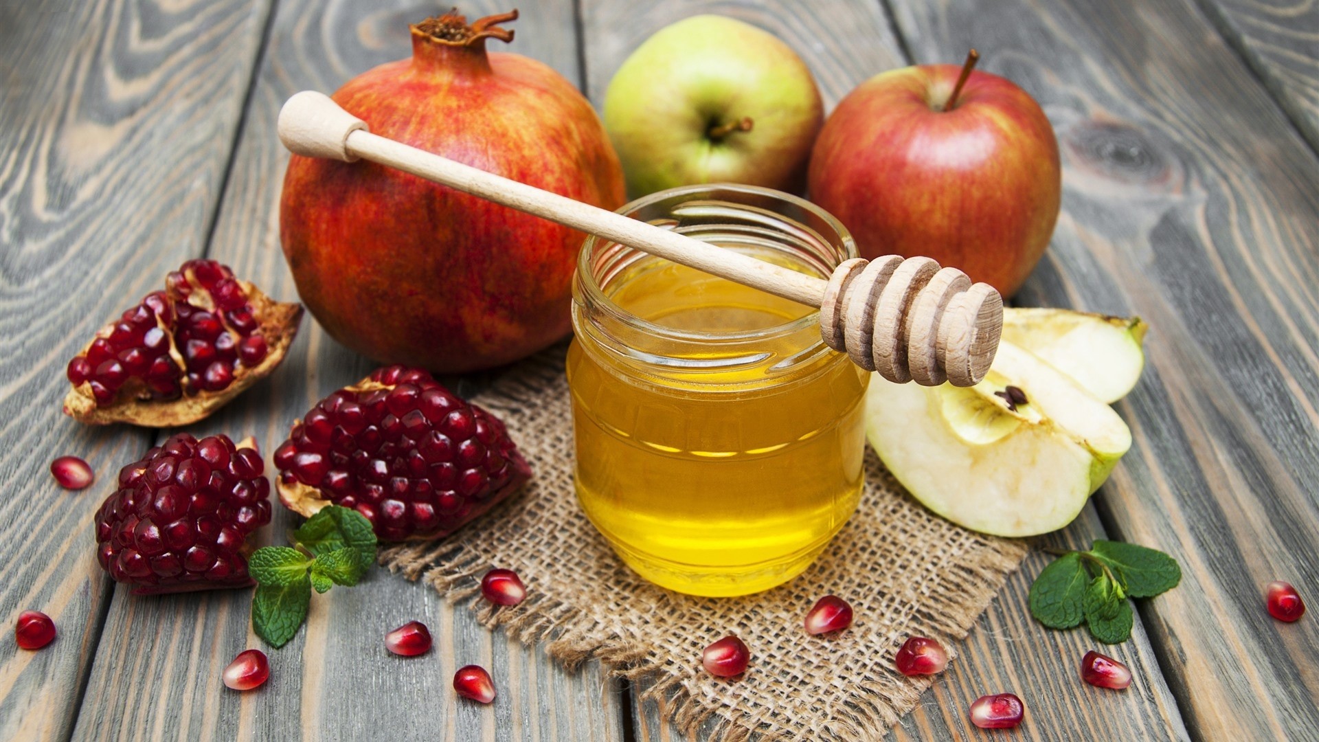 Pomegranates, apples, and honey on a wooden table HD Wallpaper