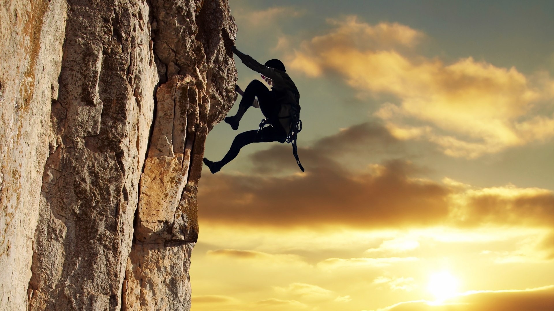 Silhouette of a climber on a rock face at sunset HD Wallpaper