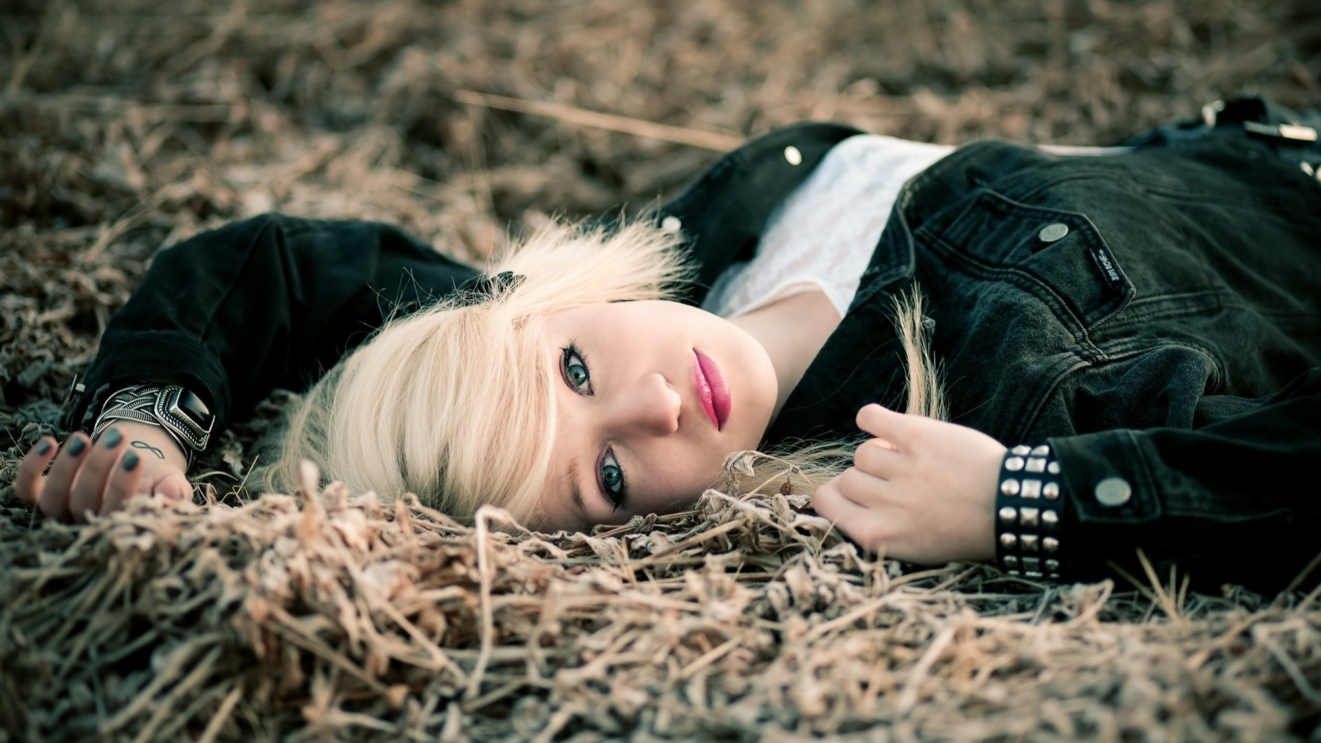 Young woman with blonde hair lying on dry grass HD Wallpaper
