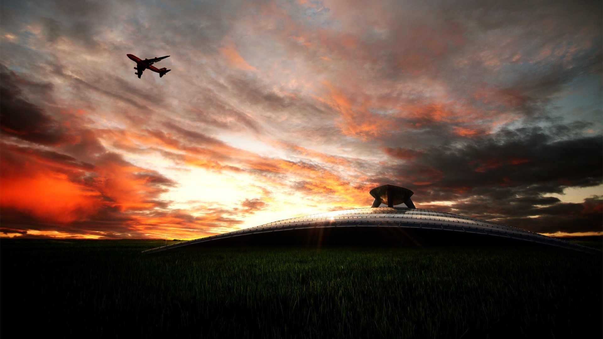 Airplane flying over a UFO-like structure at sunset HD Wallpaper