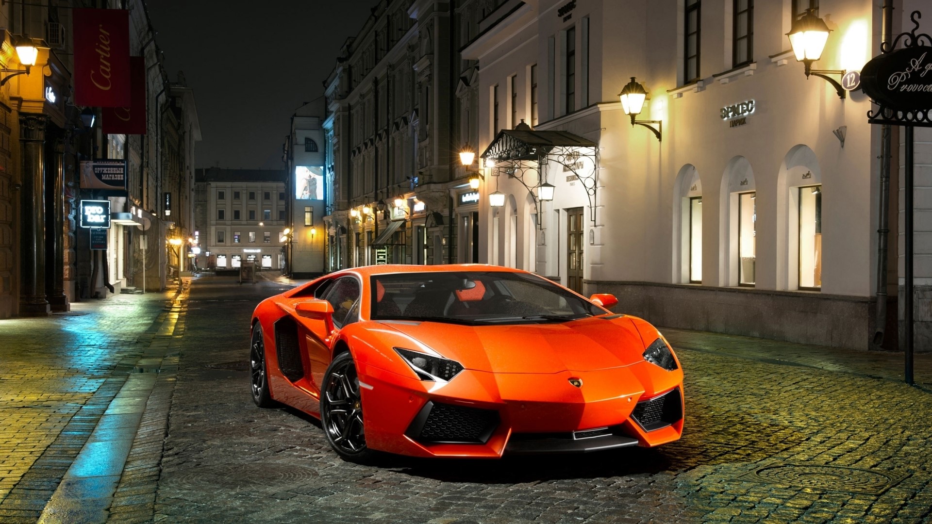 Orange Lamborghini Aventador on a cobblestone street at night HD Wallpaper
