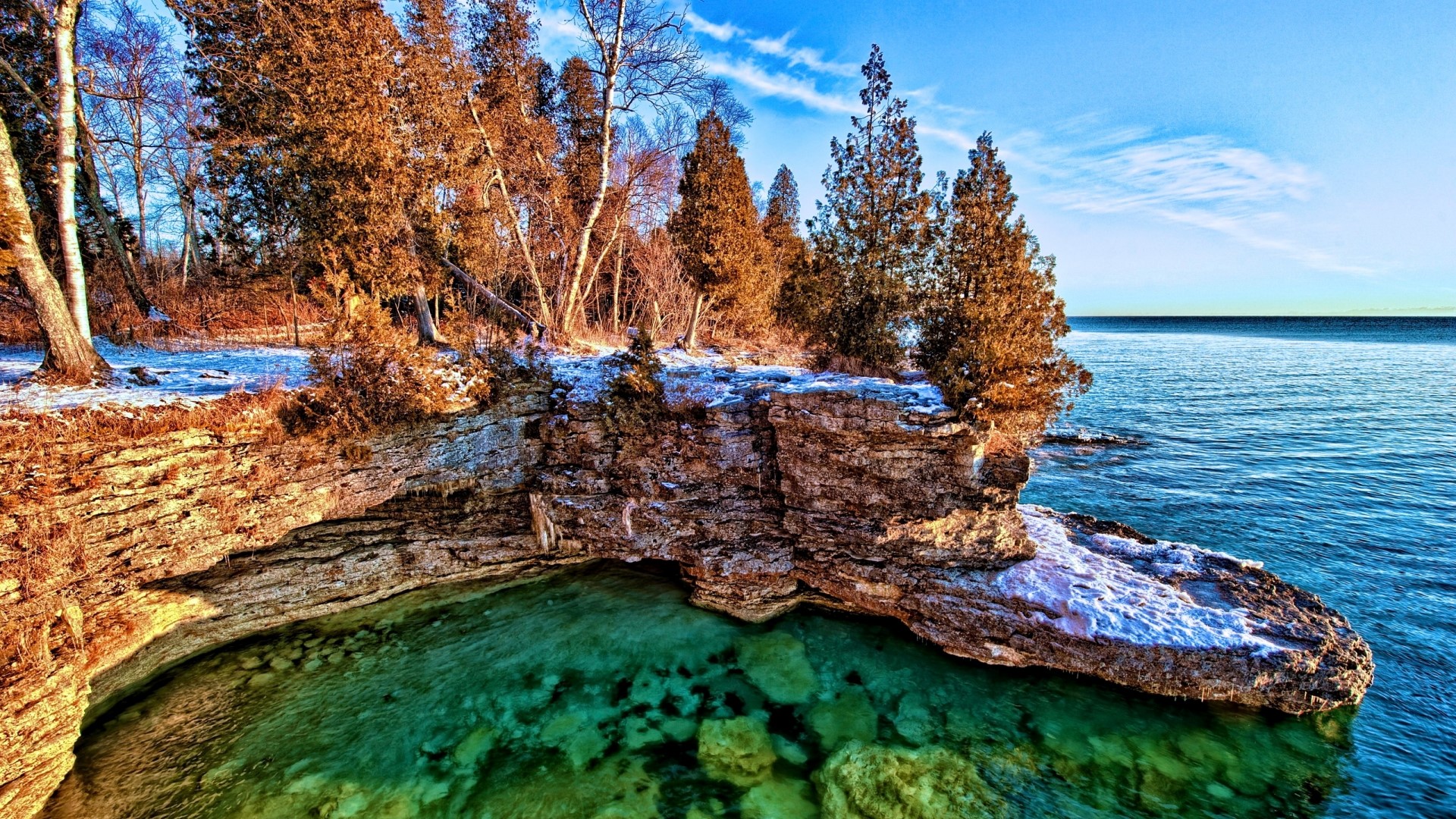 Rocky shoreline with clear turquoise water and trees HD Wallpaper