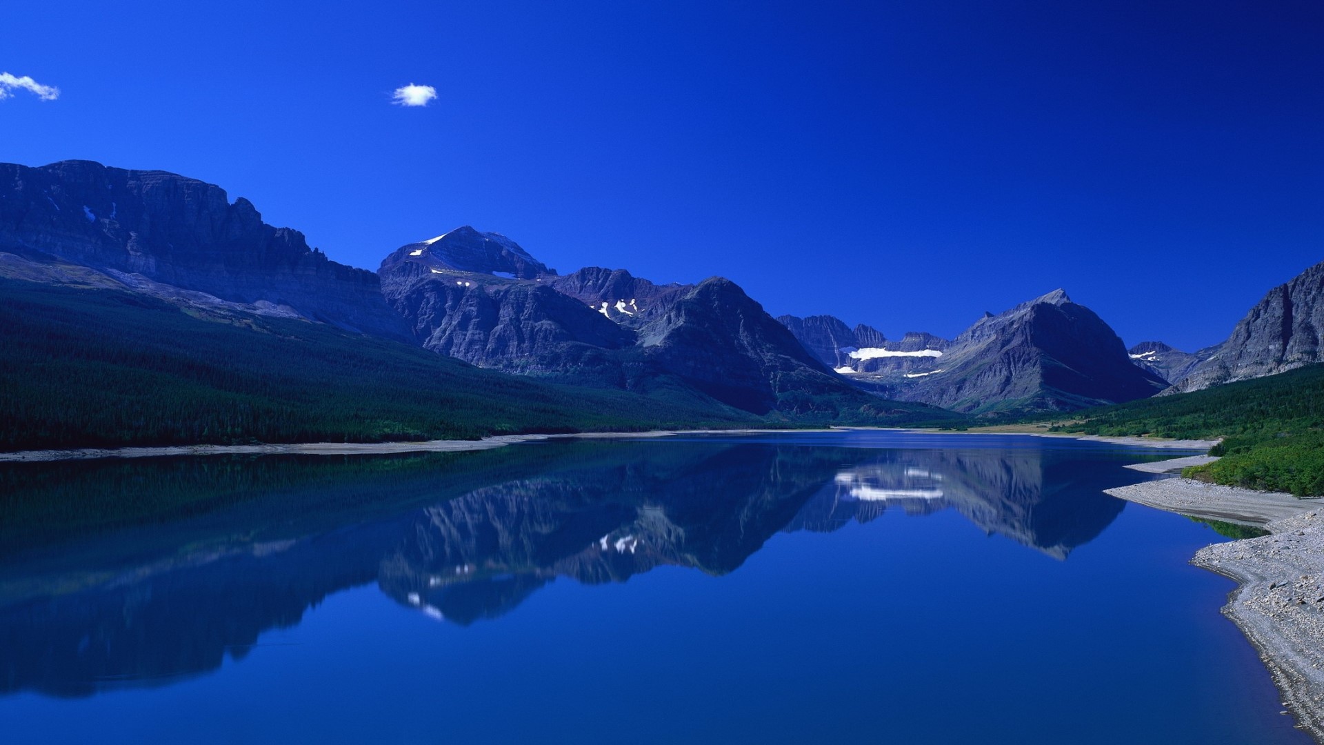 Mountains reflected in a blue lake under a clear sky HD Wallpaper