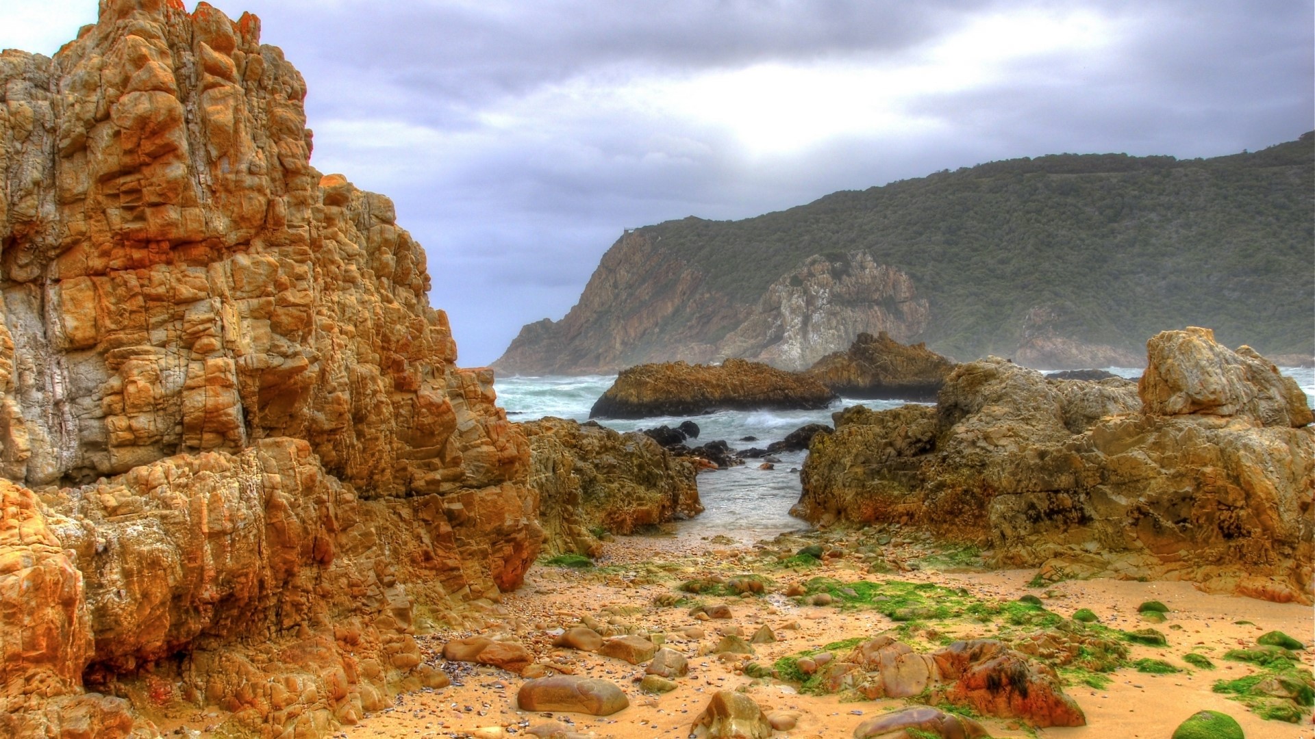 Rocky coastline with waves and green hills HD Wallpaper