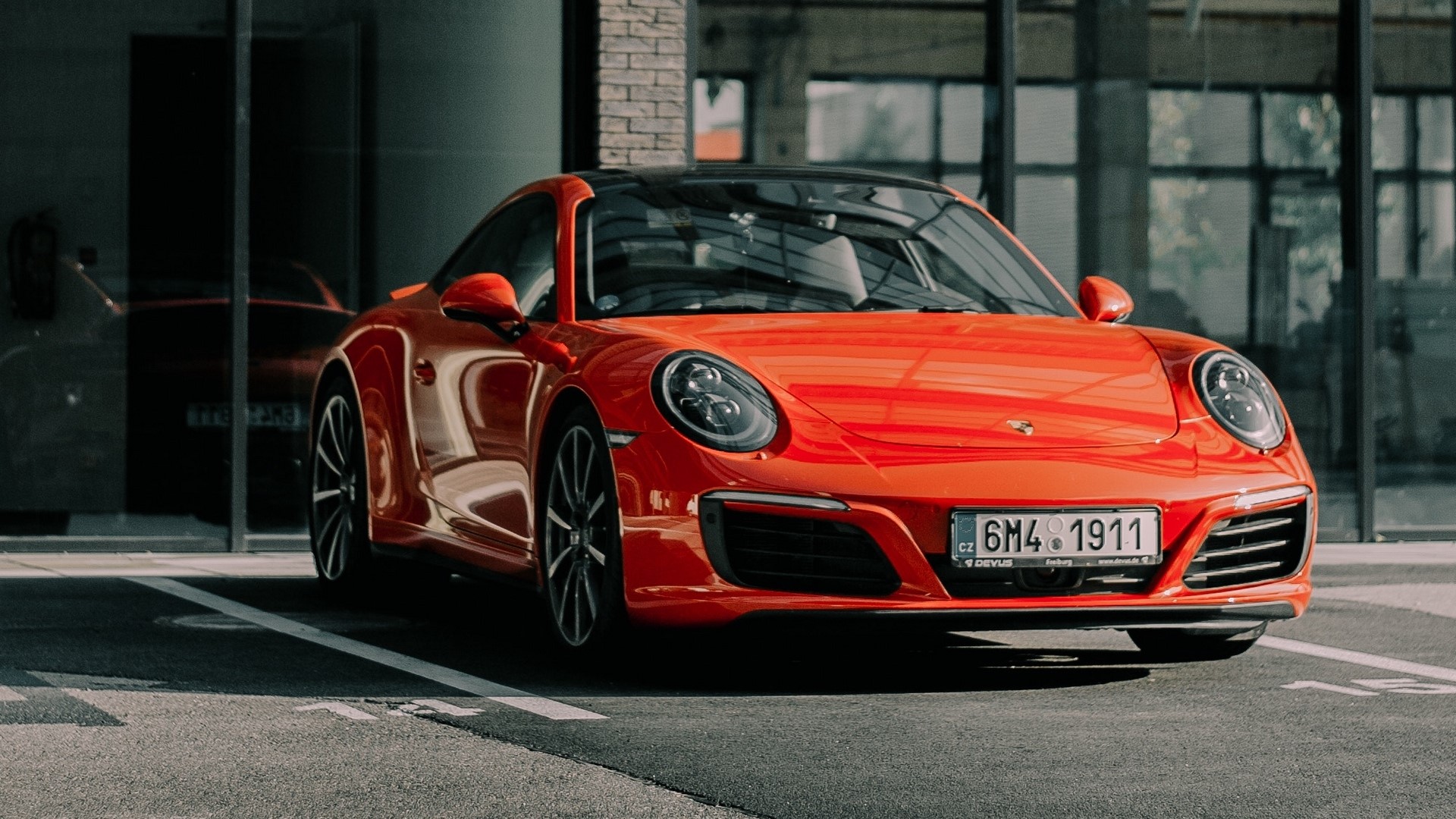 Orange Porsche 911 parked in front of a building HD Wallpaper