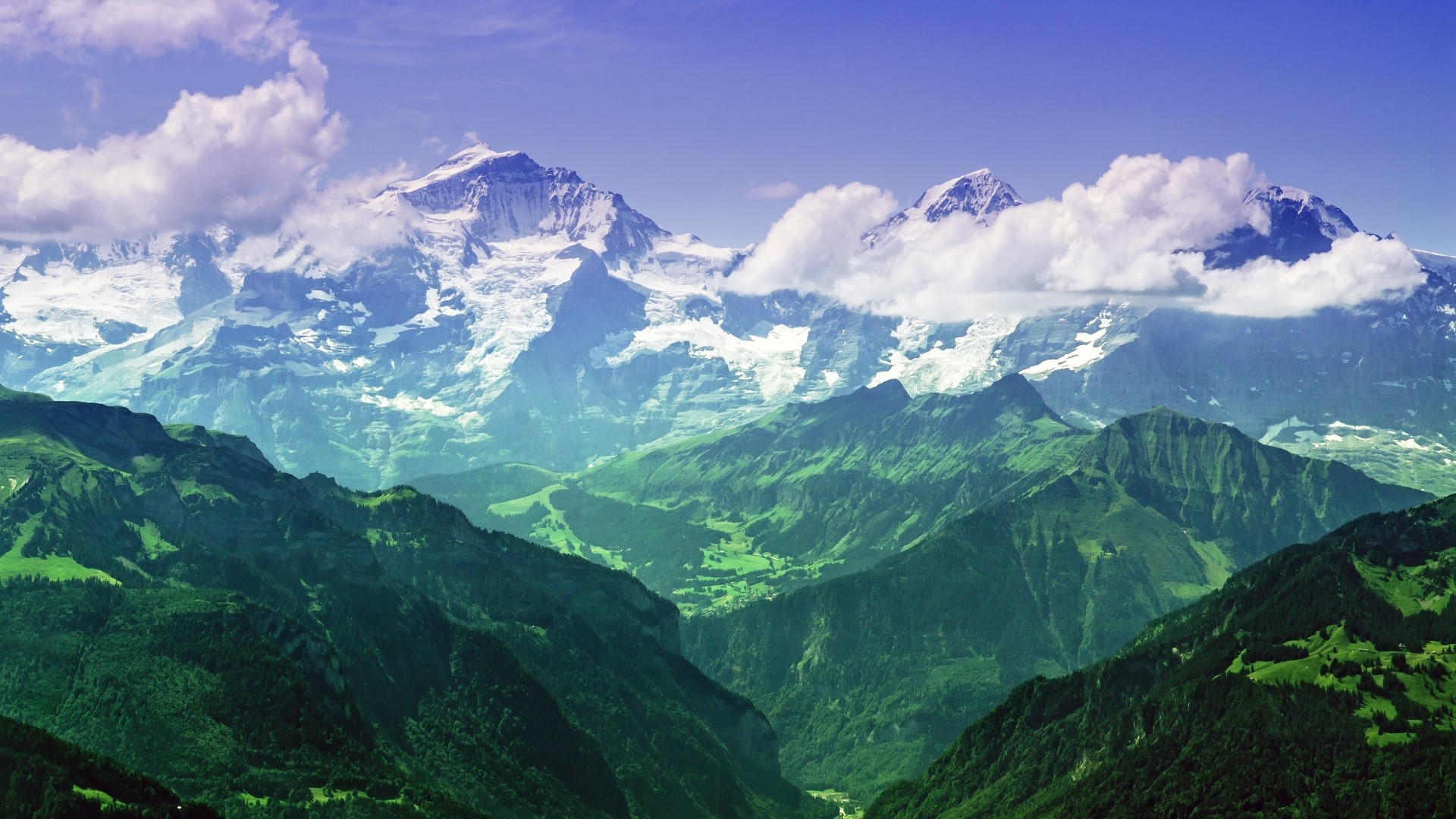 Snow-capped mountains and green valleys under a blue sky HD Wallpaper