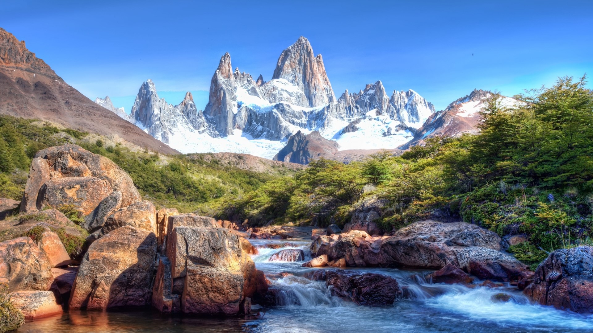 Snow-capped mountains and a river in a valley HD Wallpaper