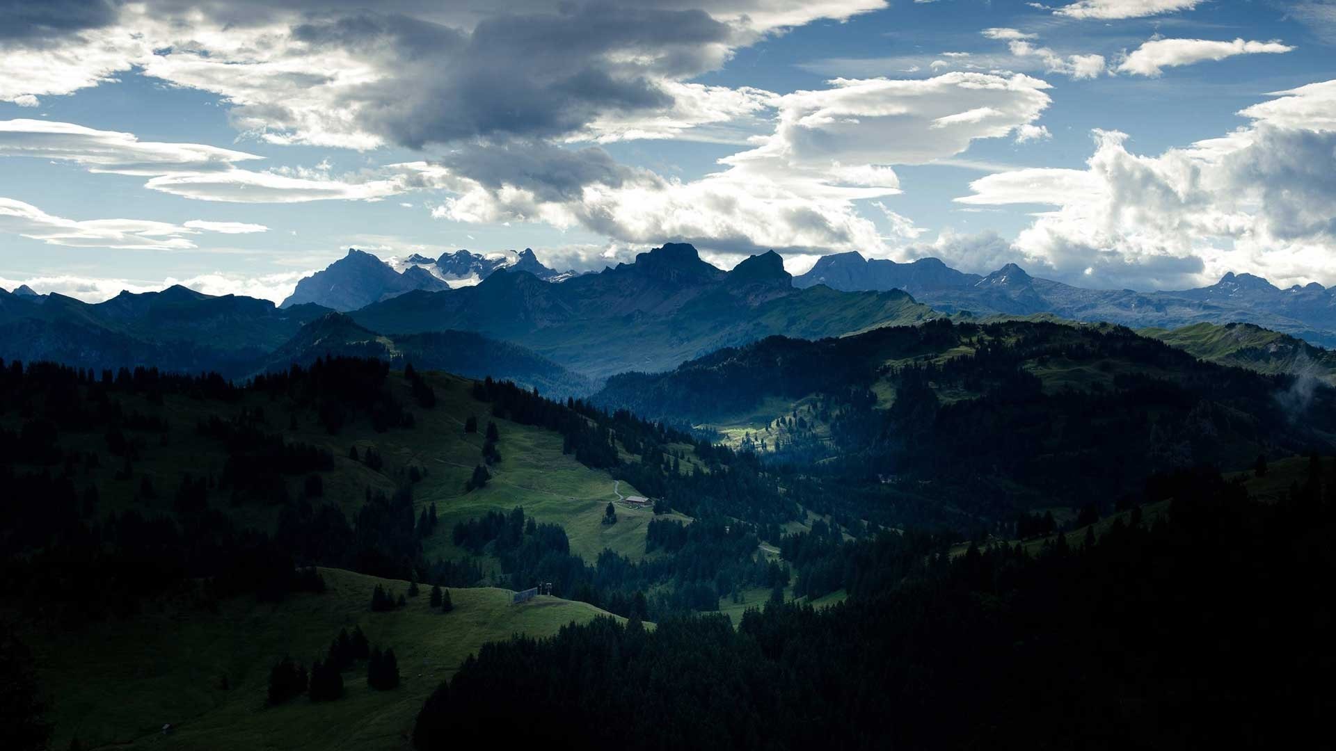 Mountain range under a cloudy sky HD Wallpaper