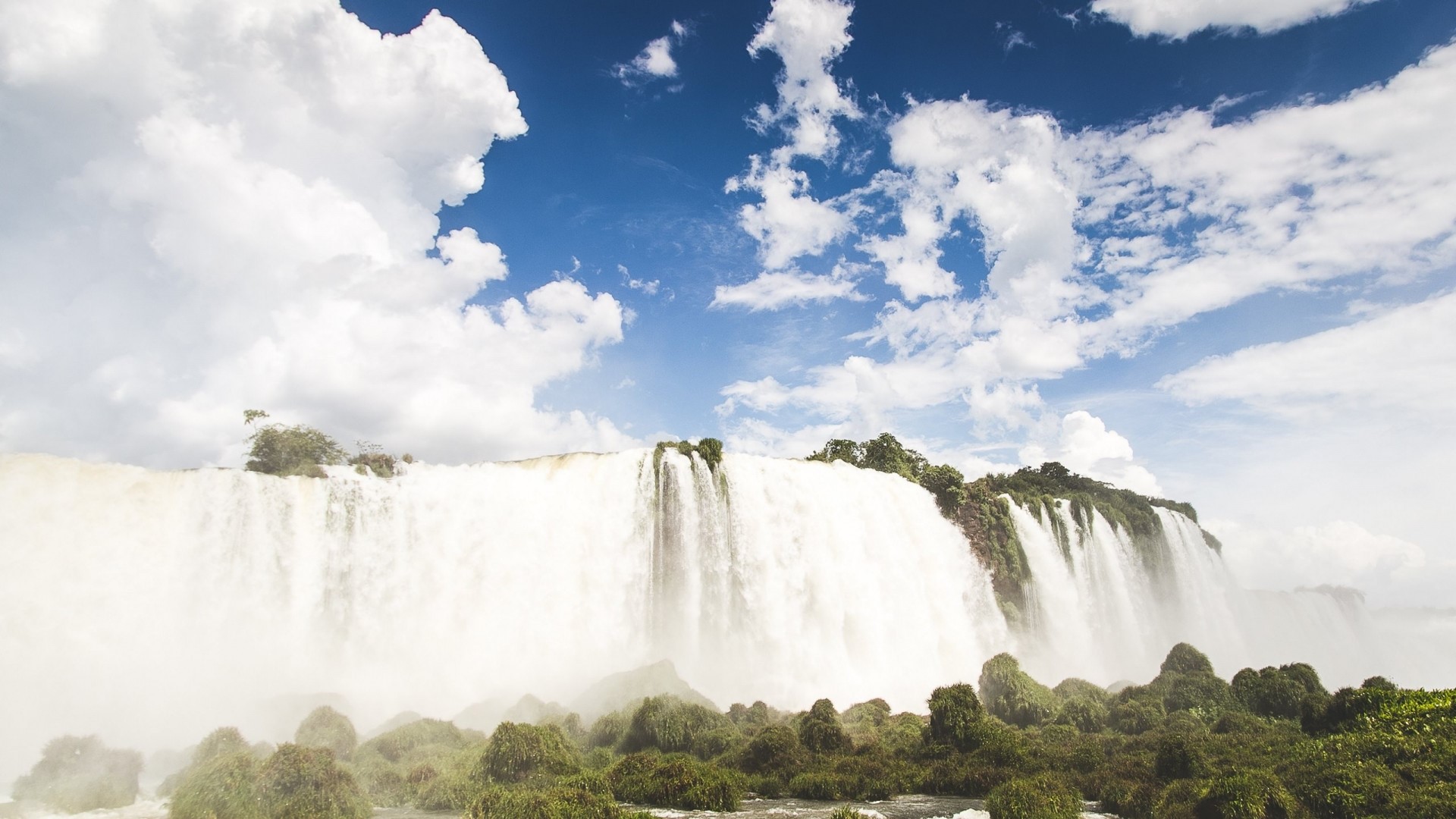 Iguazu Falls under a cloudy blue sky HD Wallpaper