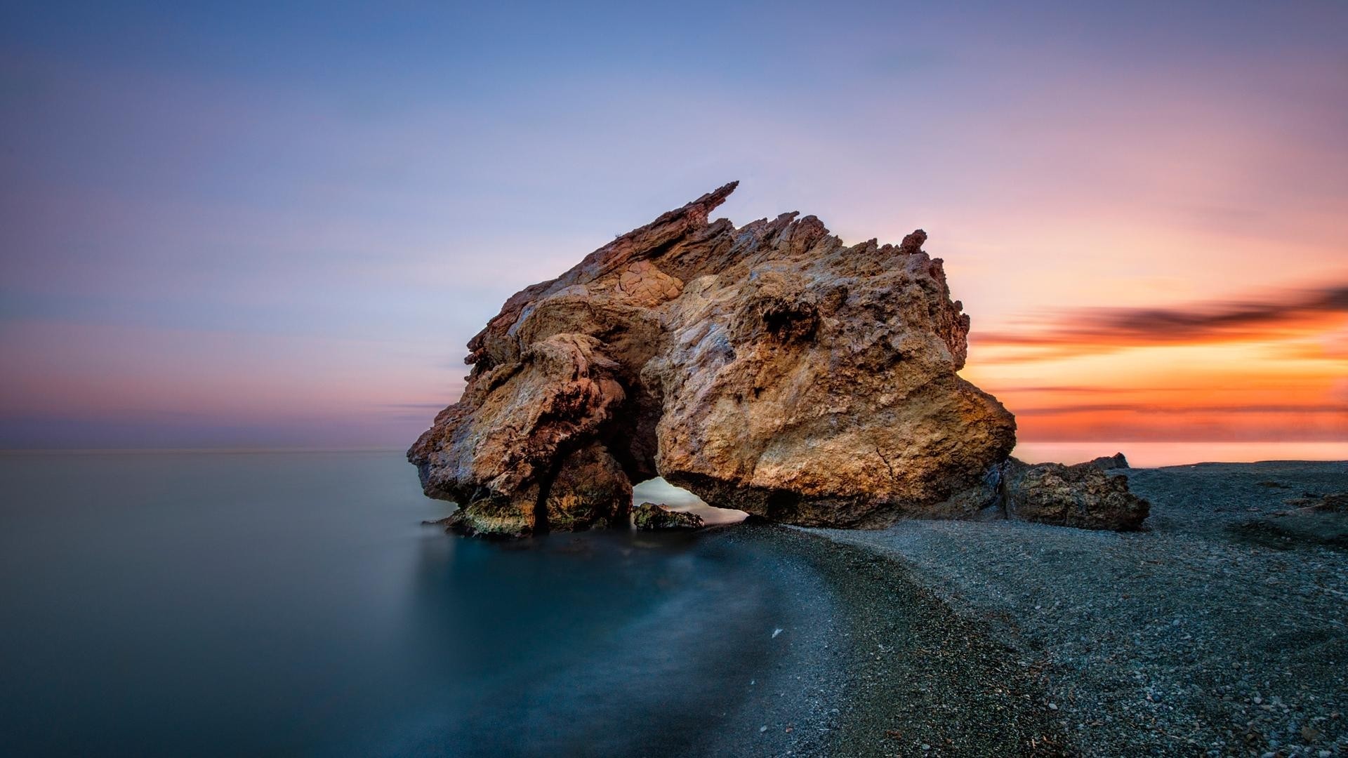 Rock formation on a beach at sunset HD Wallpaper