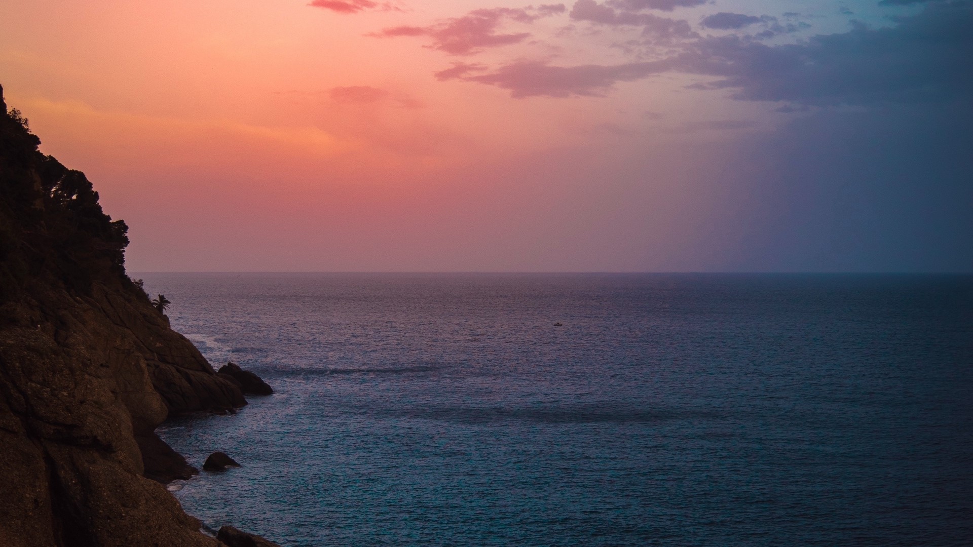 Sunset over the ocean with a rocky cliff HD Wallpaper