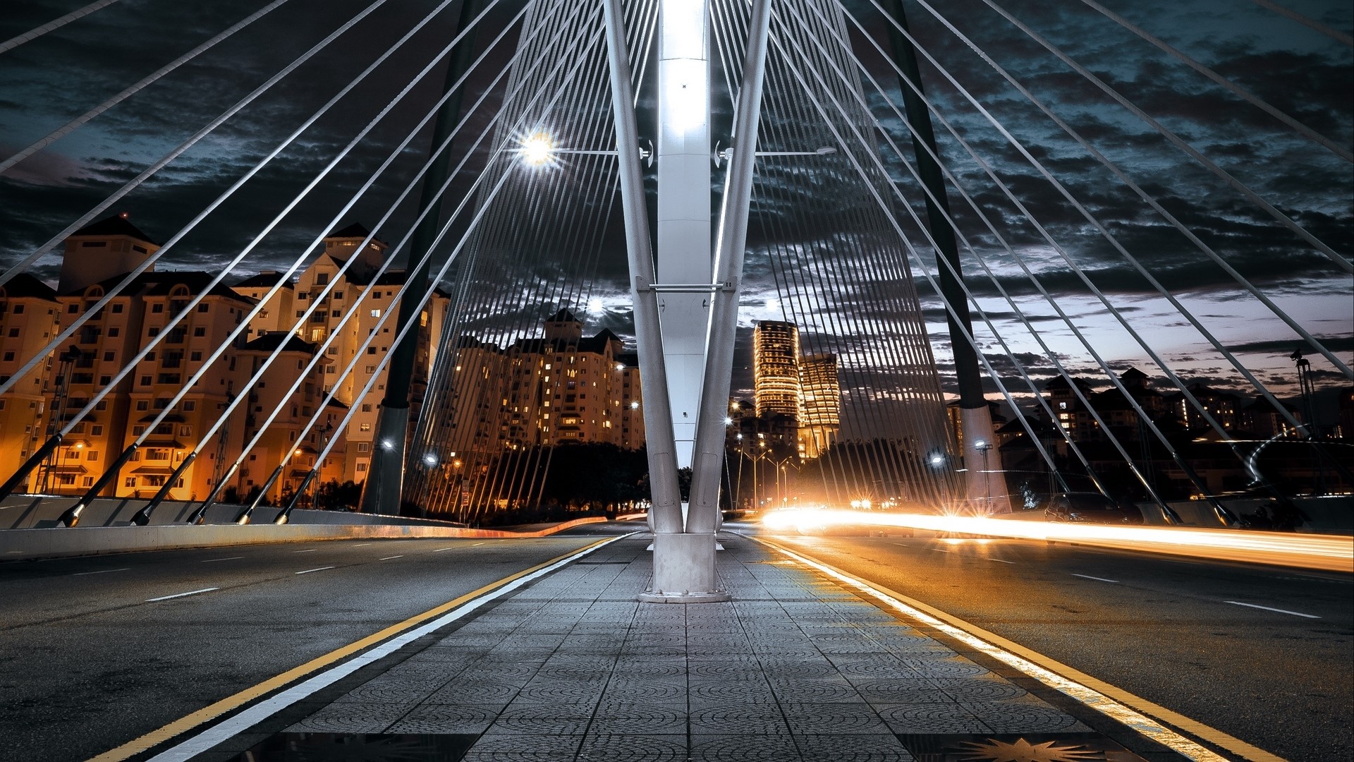 Cable-stayed bridge at night with city lights HD Wallpaper
