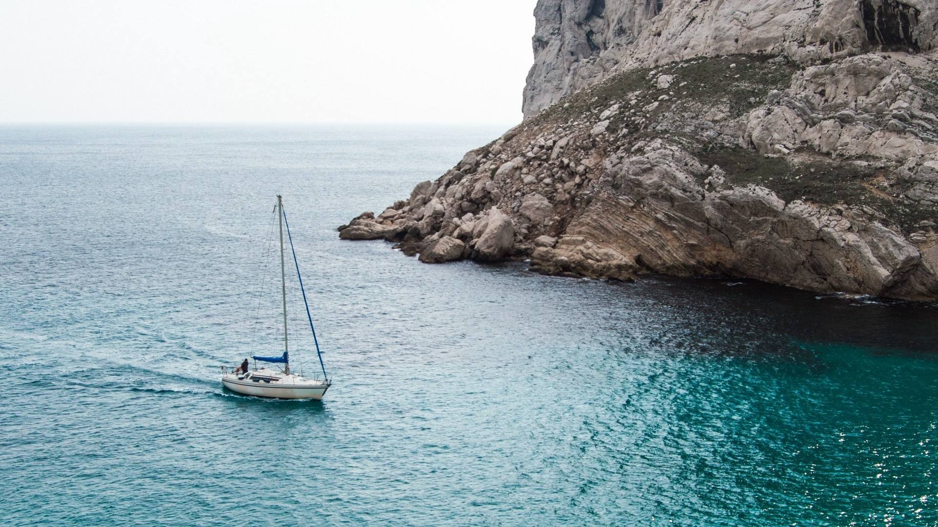 Sailboat near rocky cliff in the ocean HD Wallpaper