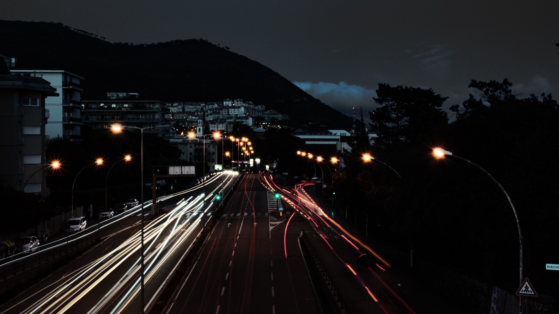 Night highway with light trails and city lights HD Wallpaper
