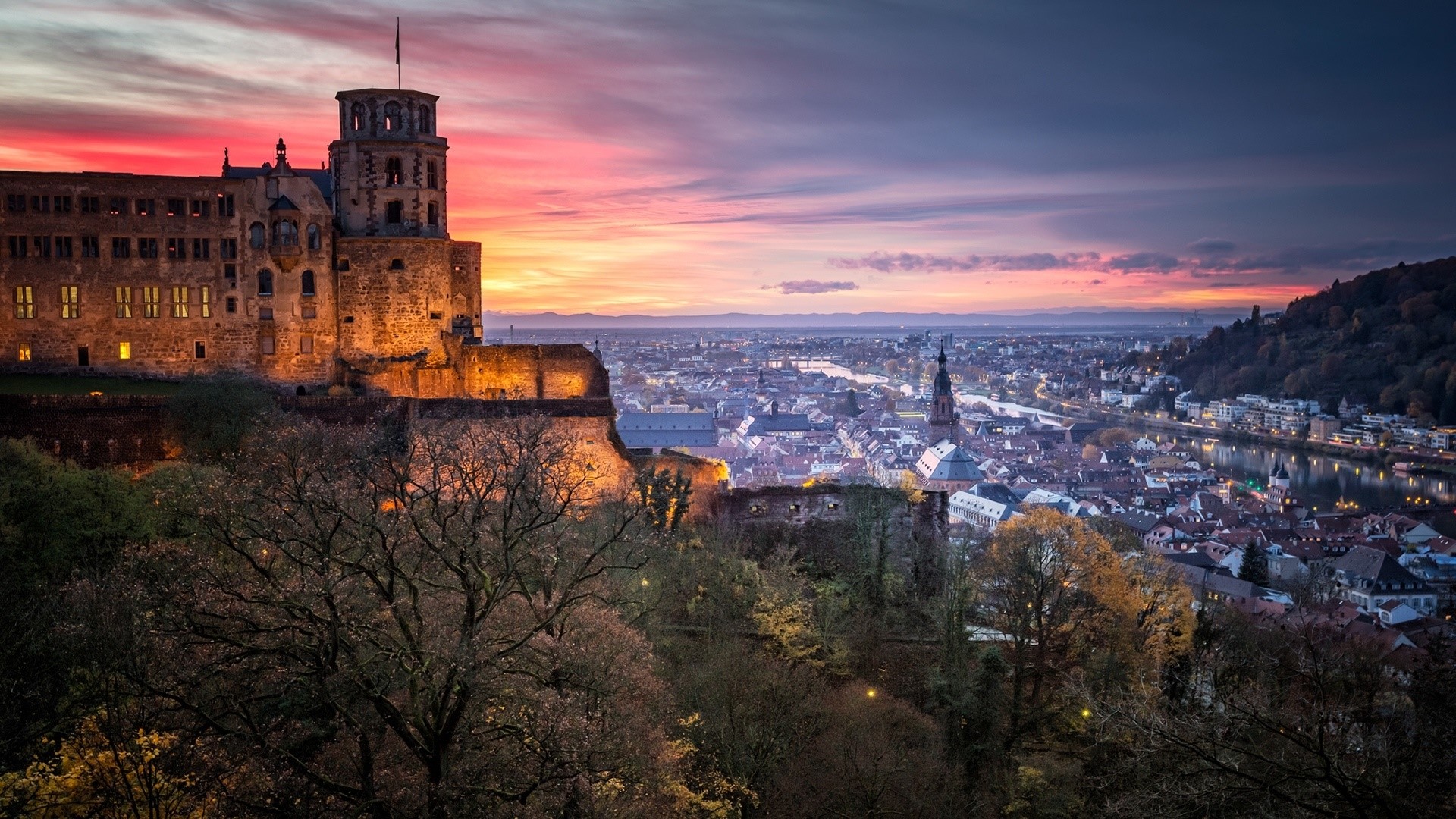 Heidelberg Castle overlooking a city at sunset HD Wallpaper