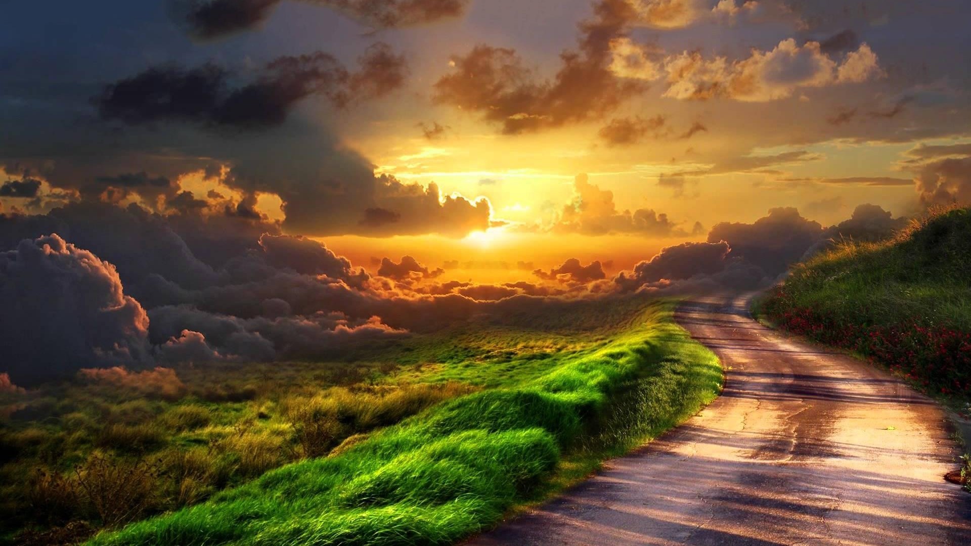 Sunset over a grassy hill with a road HD Wallpaper
