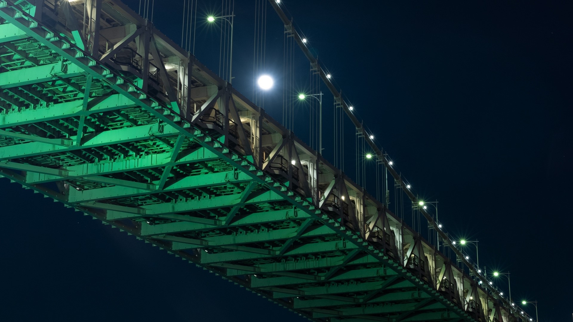 Bridge illuminated with green lights at night with moon HD Wallpaper