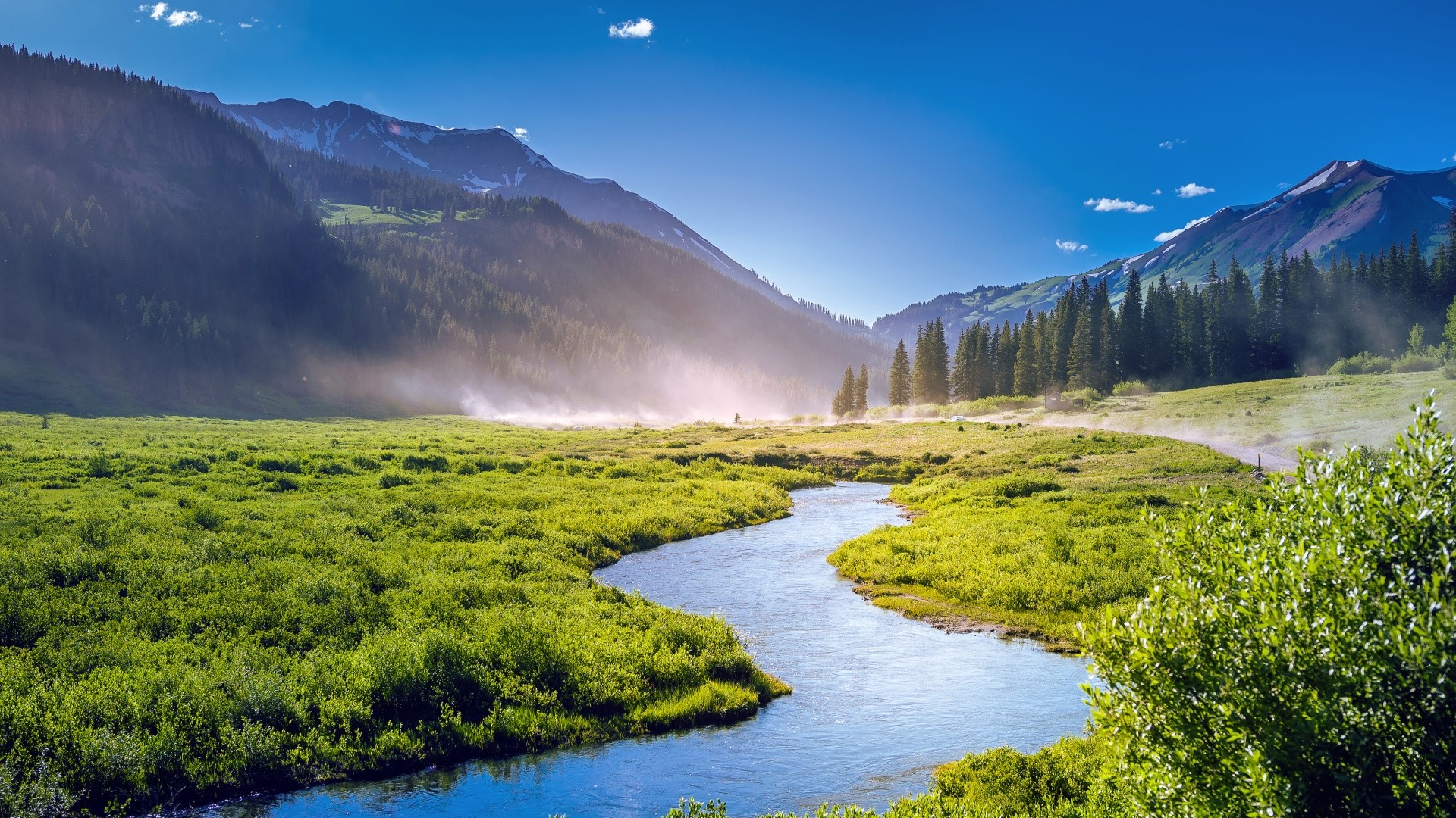 River flowing through a green valley with mountains HD Wallpaper