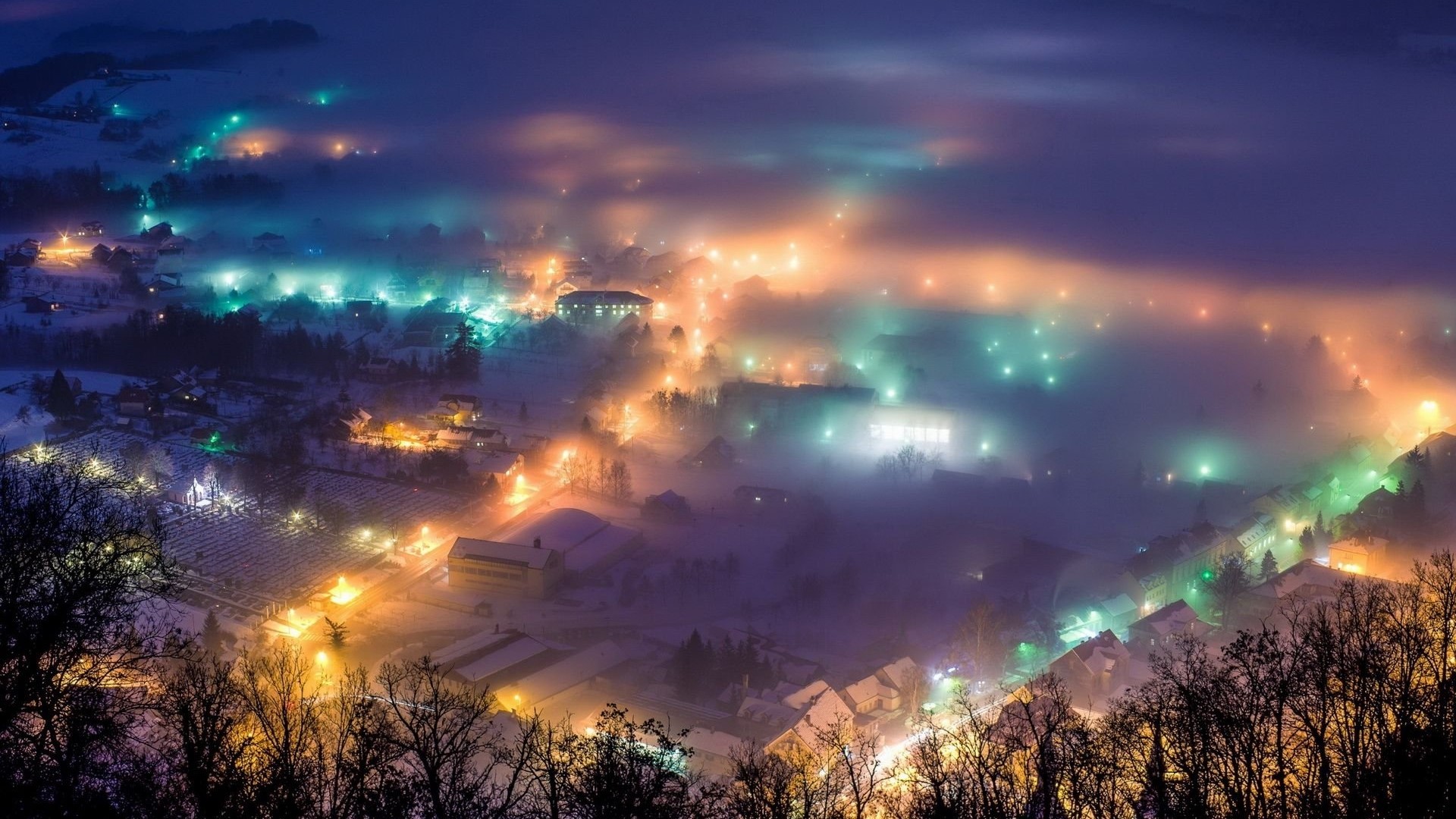 Aerial view of a town at night in the fog HD Wallpaper
