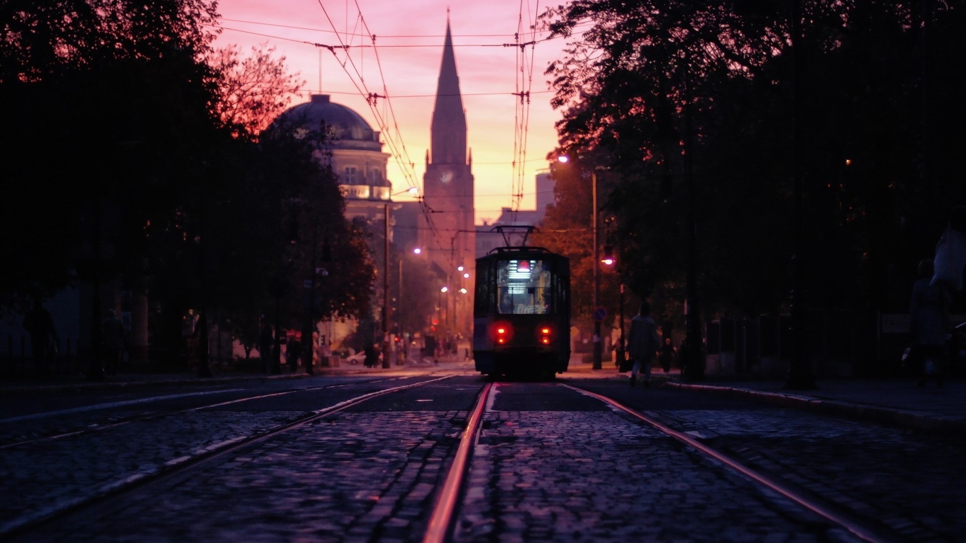 Tram on cobblestone street at sunset HD Wallpaper