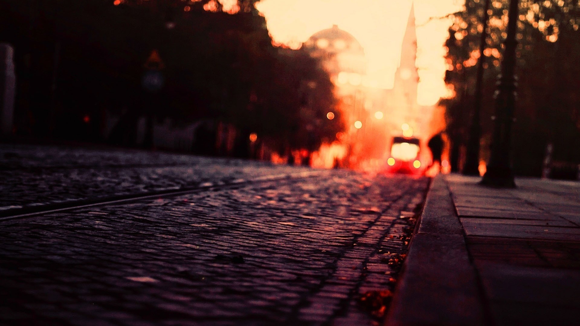 Streetcar at sunset on cobblestone street HD Wallpaper